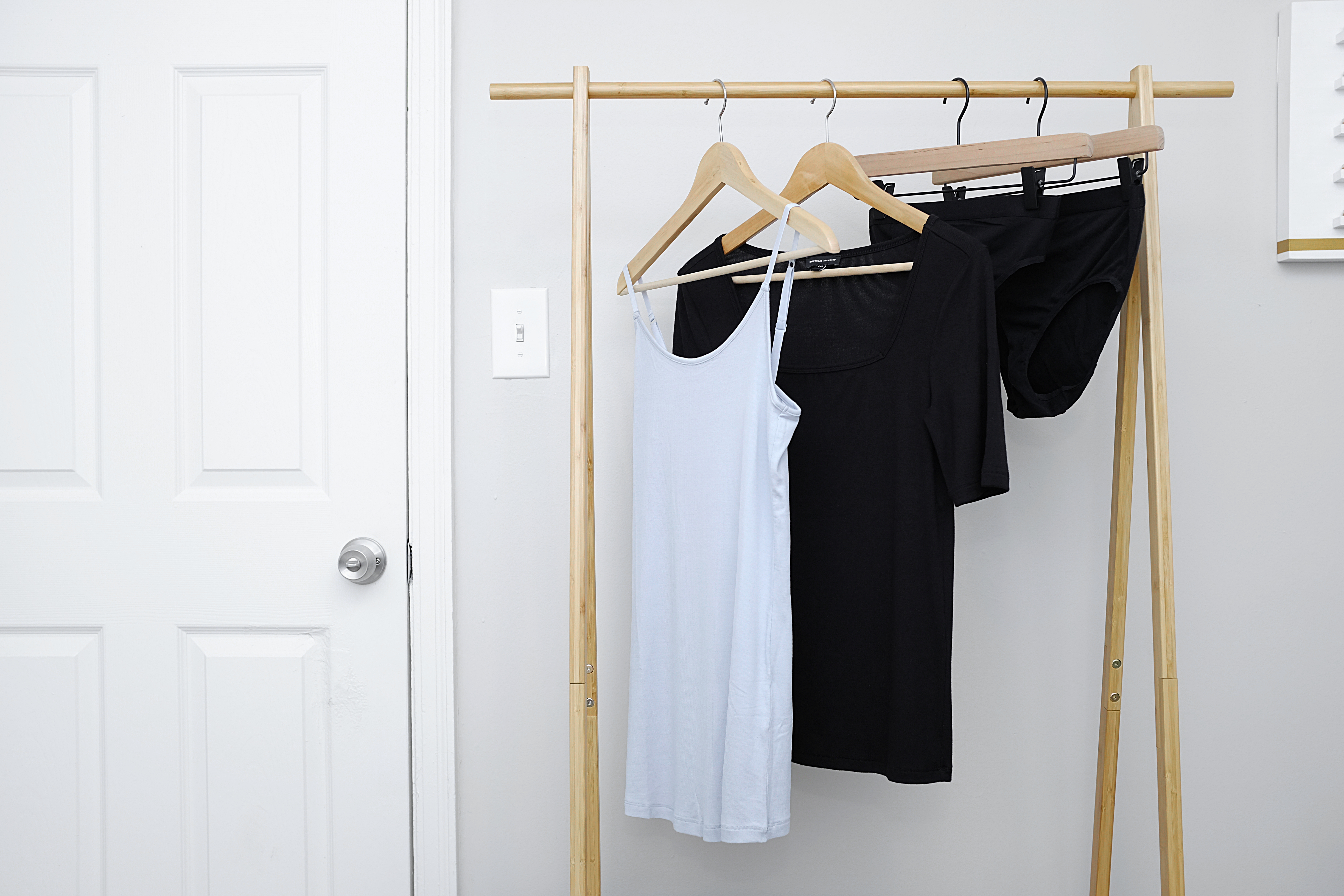 Four garments from Universal Standard hang on a clothing rack