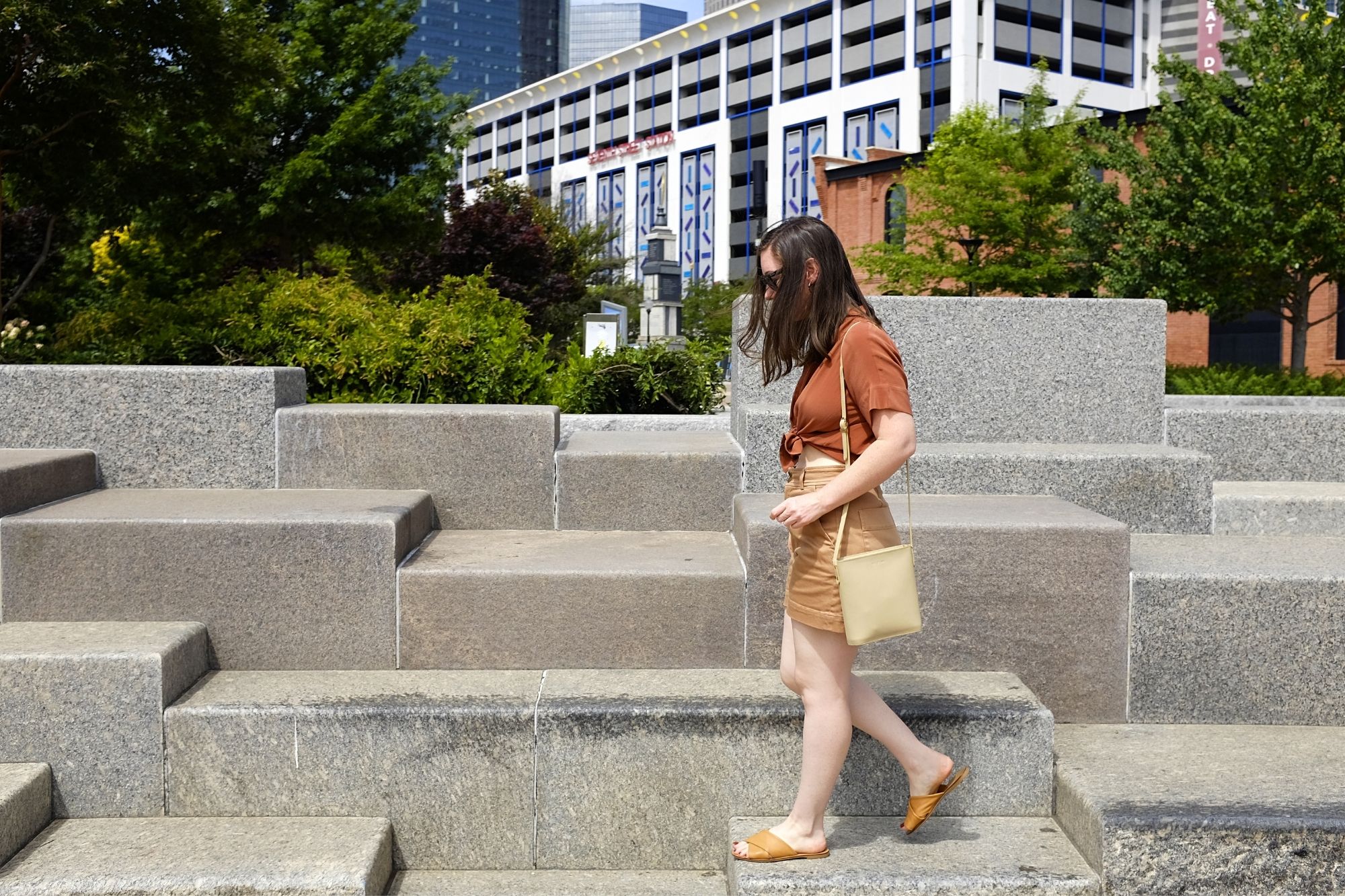 Alyssa walks on stone steps and is wearing the clean silk square shirt and the way high shorts