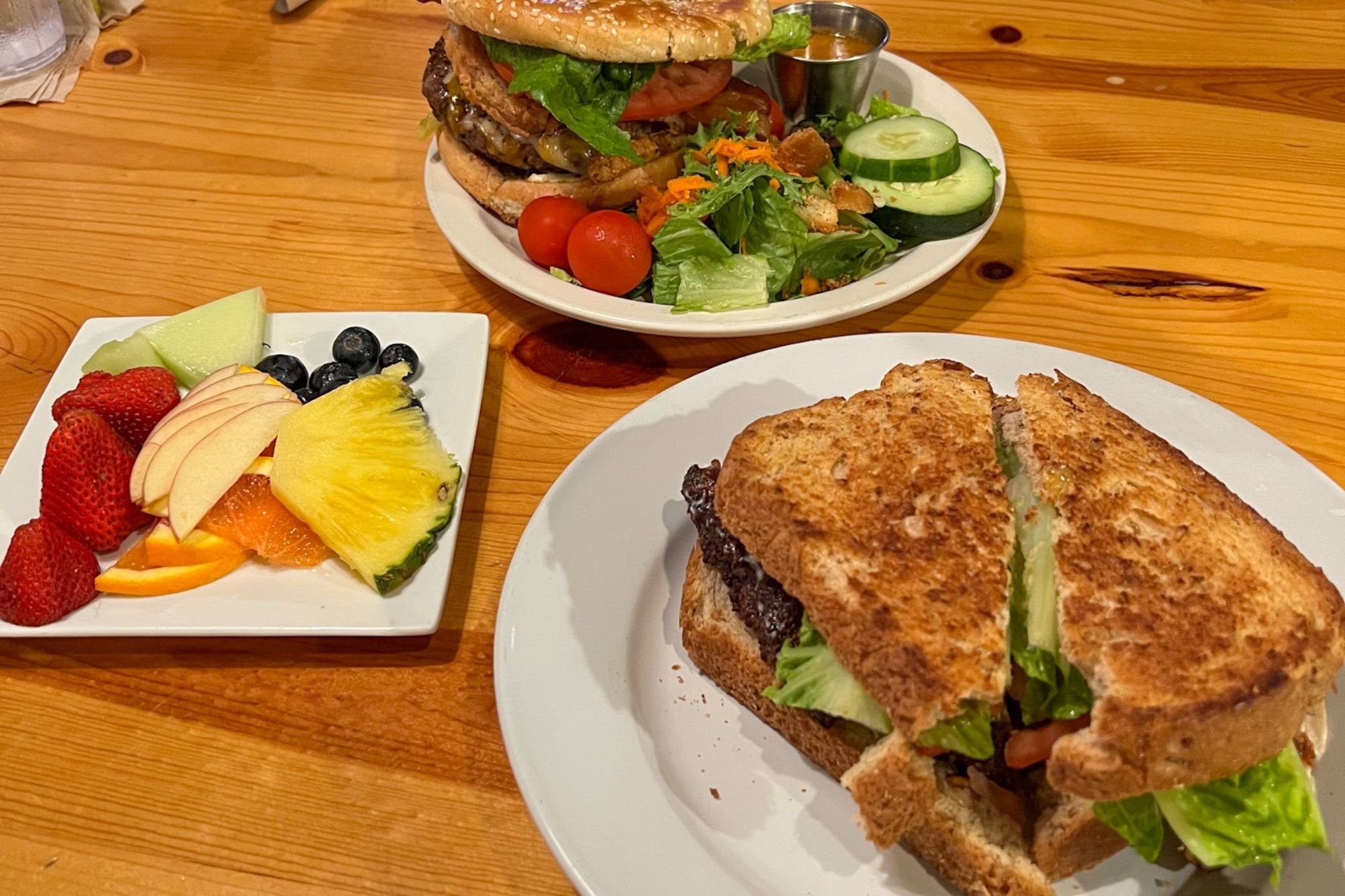 A burger, a sandwich, and a fruit plate