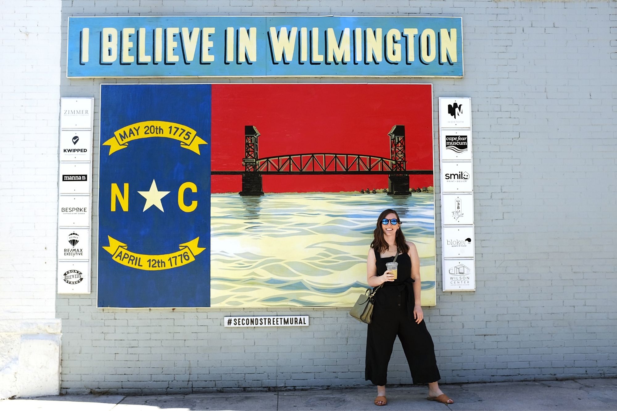 Alyssa stands in front of a mural that reads "I believe in Wilmington"