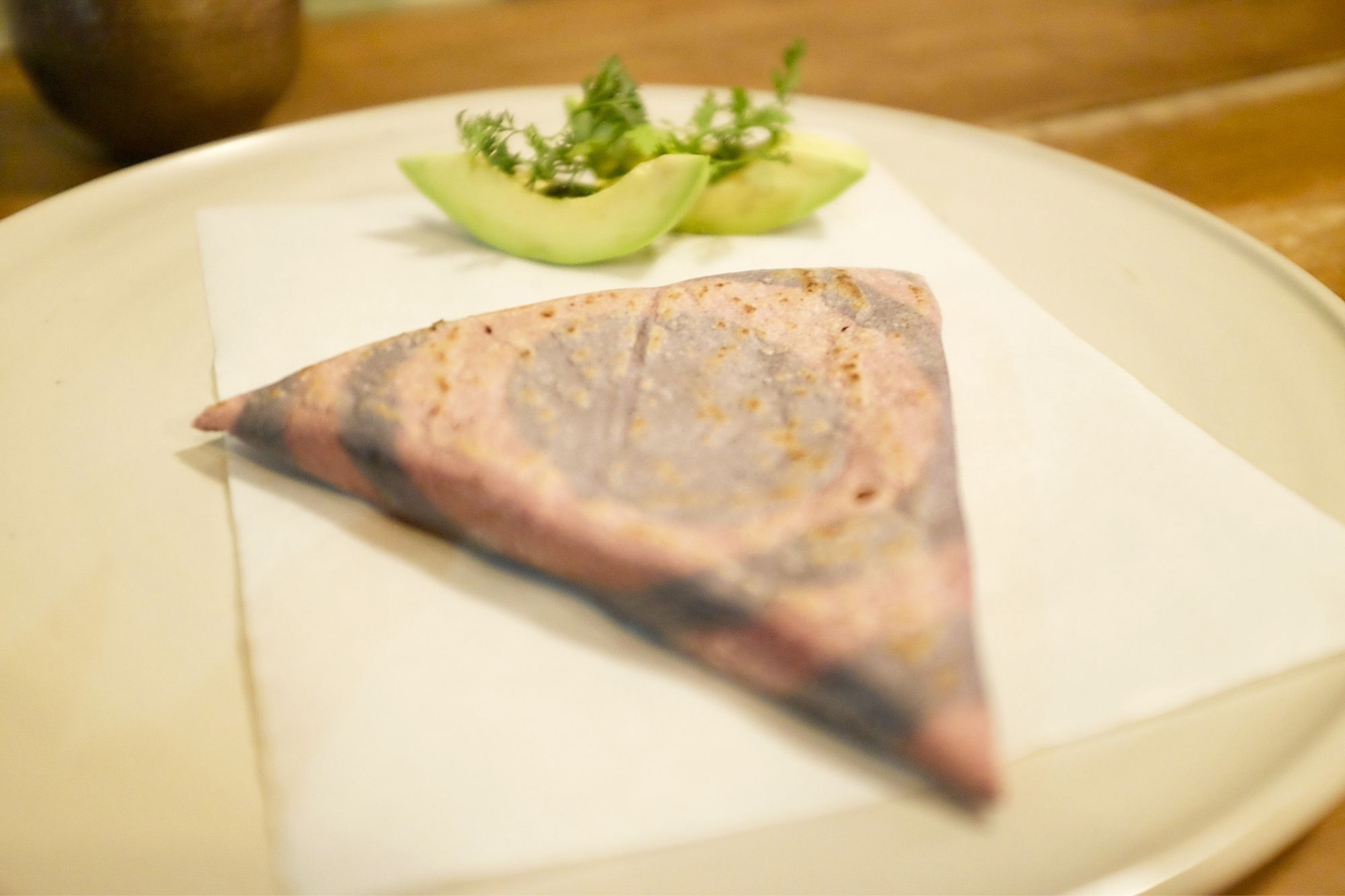 A triangle-shaped piece of masa decorated with rings of pink and purple in the center, and two avocado slices