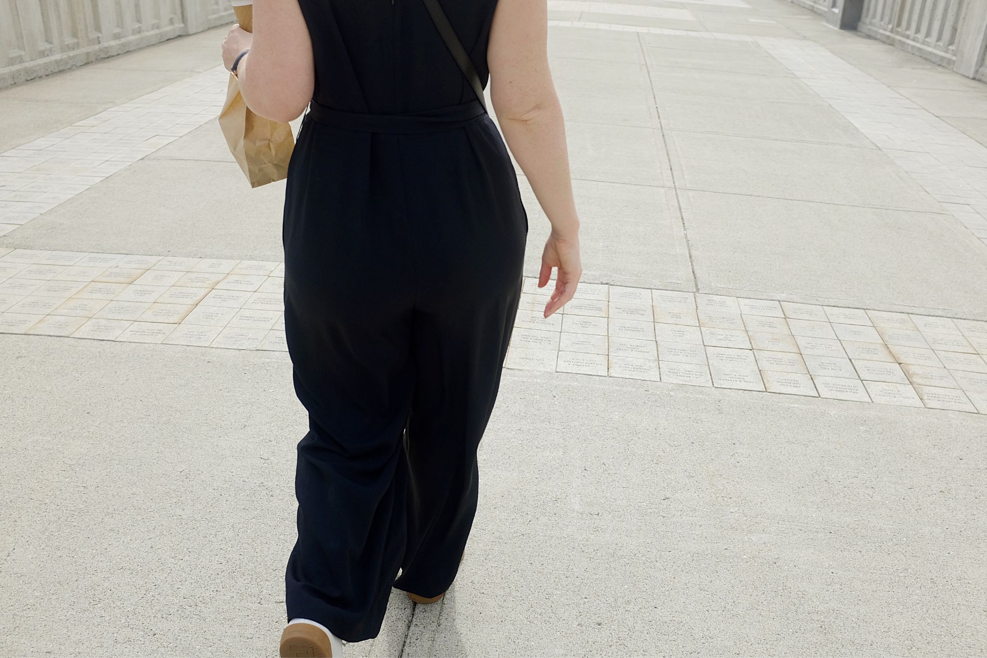 Alyssa walks with a bag of doughnuts, facing away from the camera