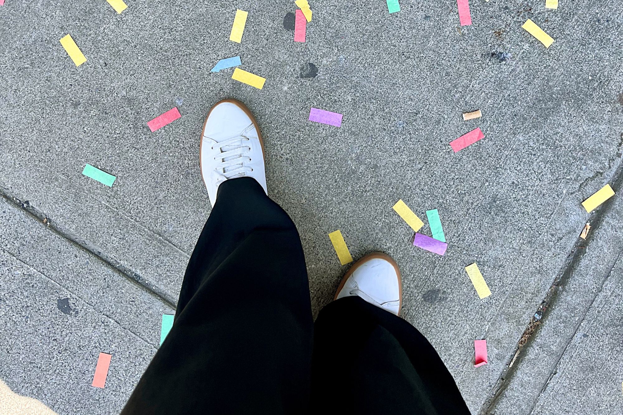 Black jumpsuit, white shoes, and confetti on the ground