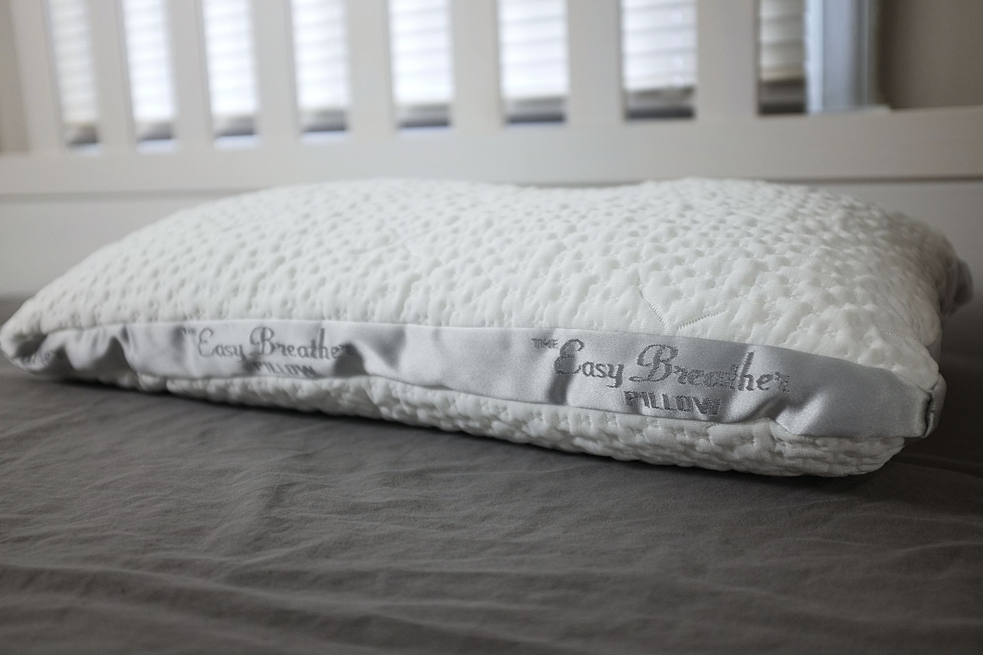 The Easy Breather Pillow sits at the head of a bed with grey sheets