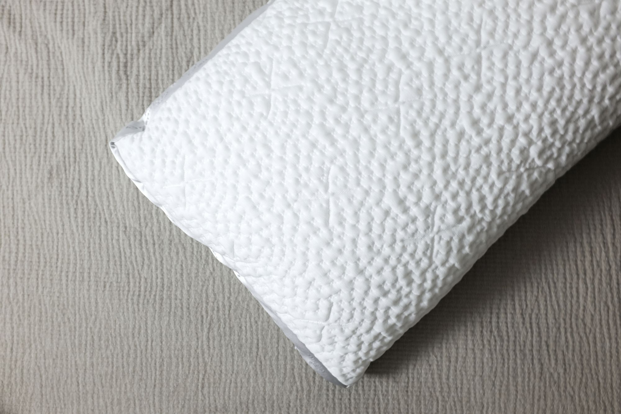 The Easy Breather Pillow on a grey comforter