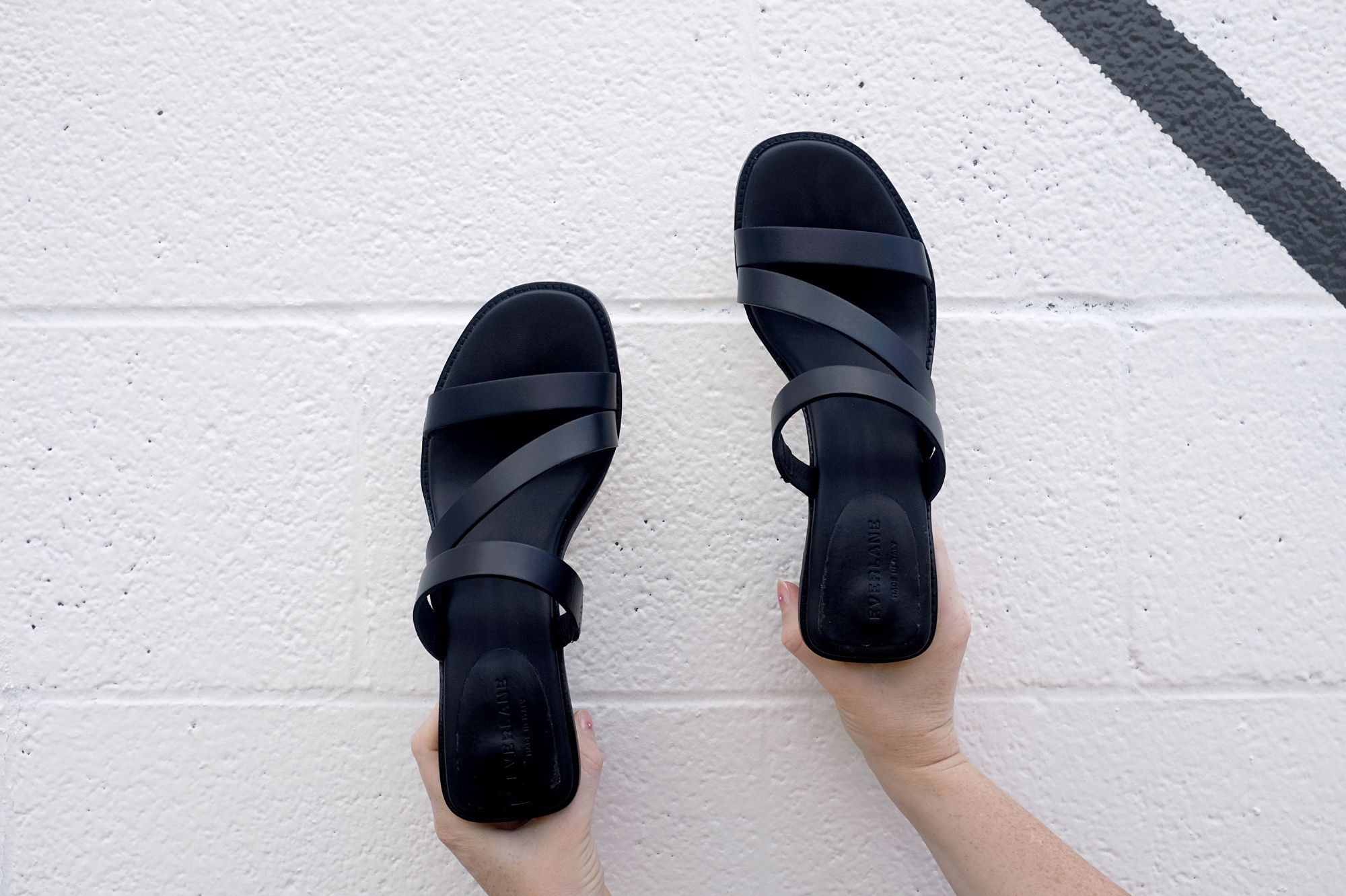 A pair of hands holds the Italian Leather Tourist Heel in front of a wall