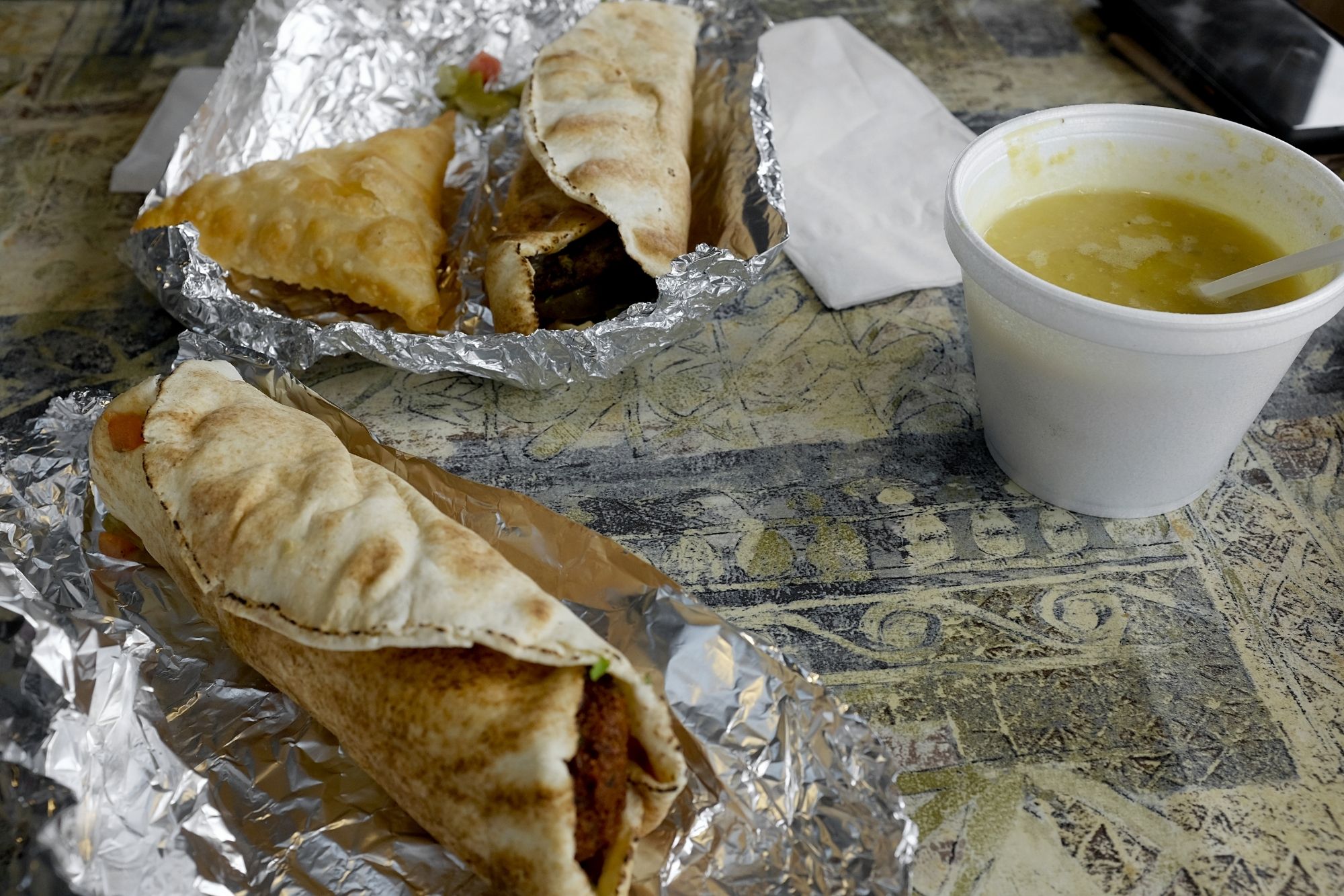 Falafel pita and lamb pita sandwiches with a side of lentil soup and a samosa