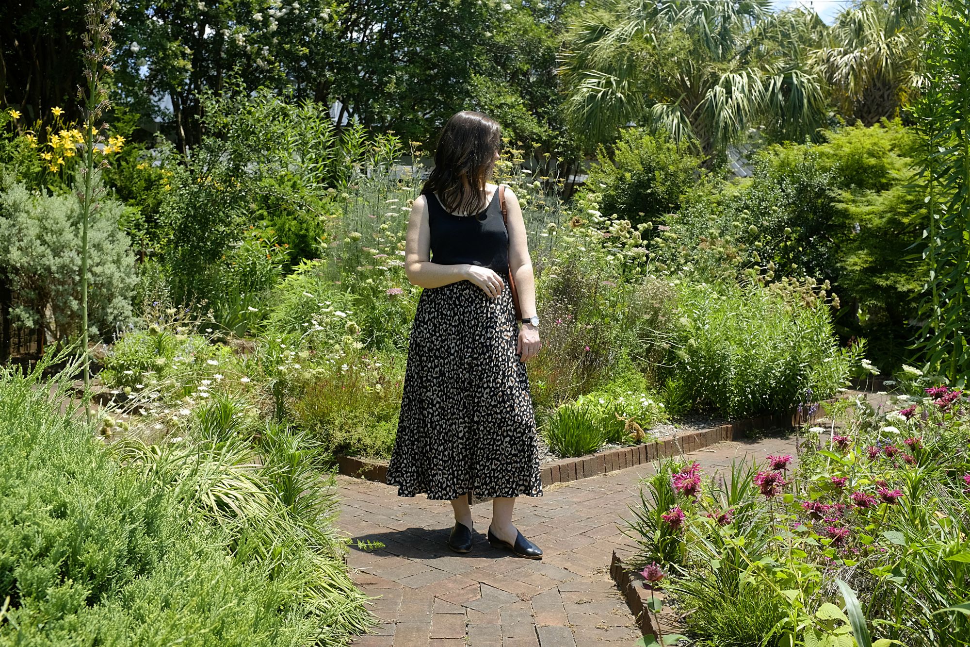 Alyssa wears a black tank, patterned skirt, and black leather shoes