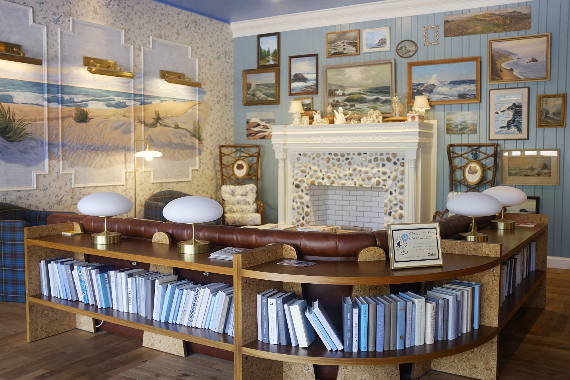 View of the lobby at the Graduate Hotel in Chapel Hill - there are lots of seaside prints on the walls and a non-functioning fireplace