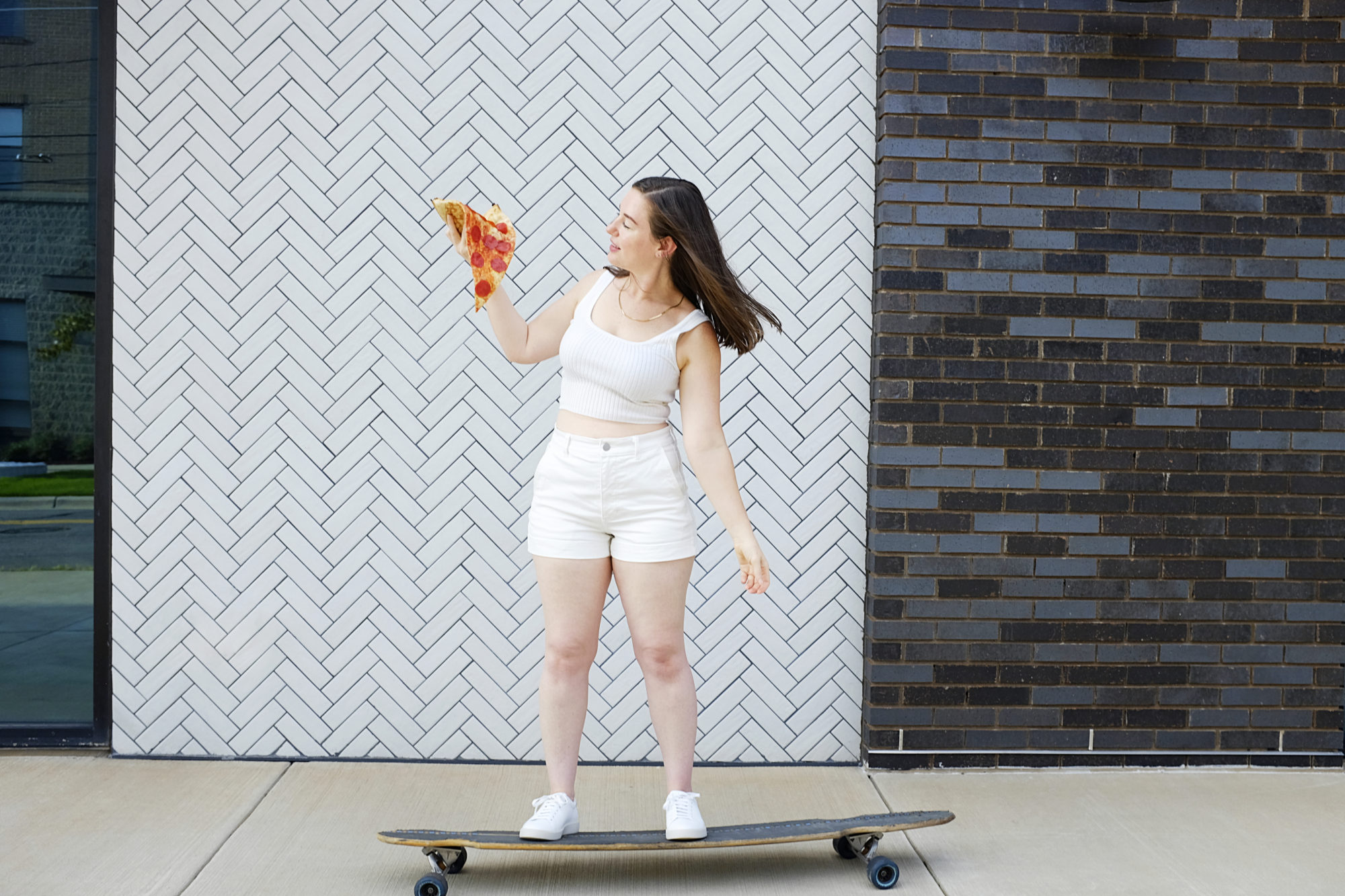 Alyssa wears The Cotton Merino Cami on a skateboard with a piece of pizza