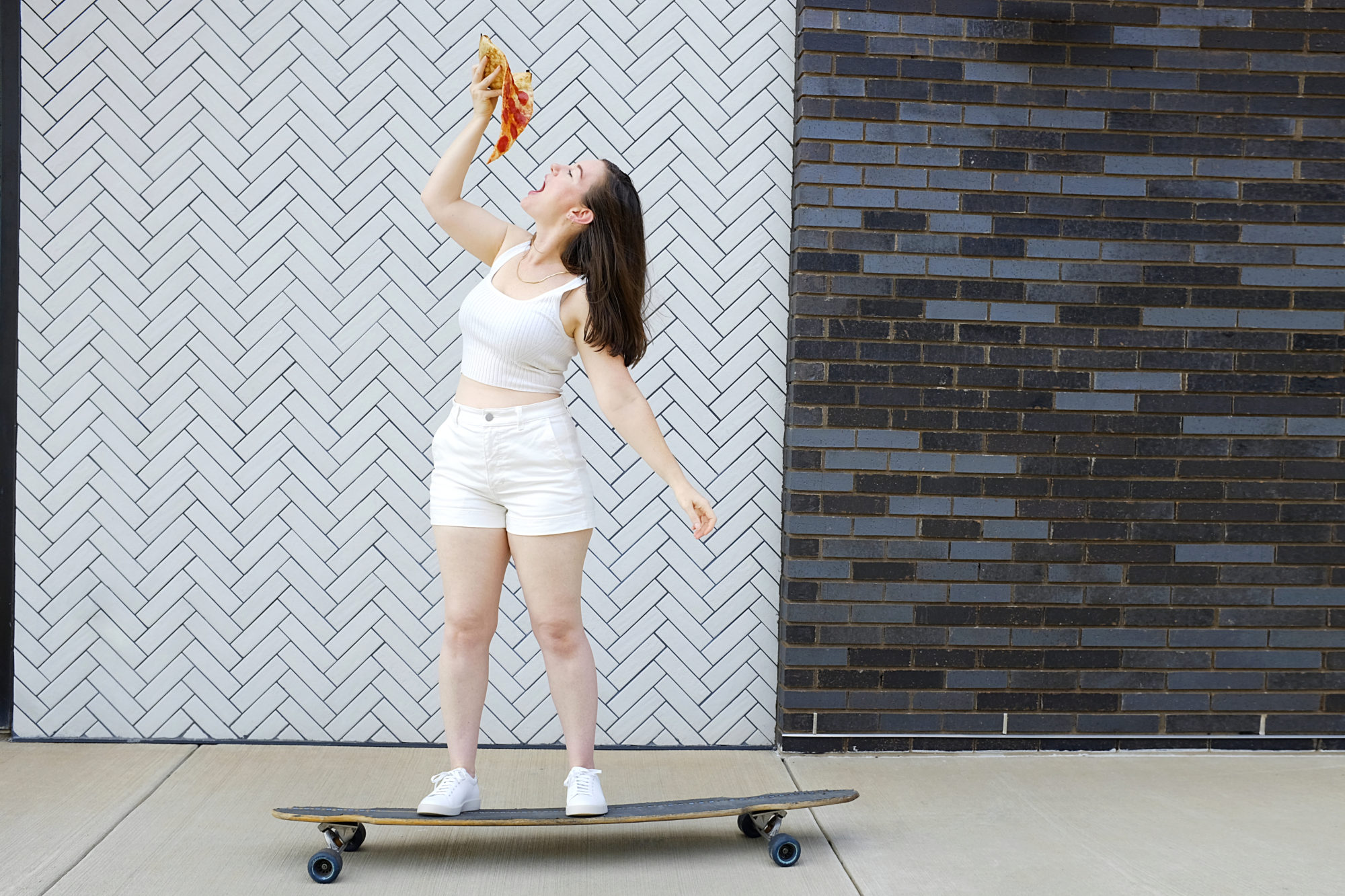 Alyssa skateboards while holding pizza
