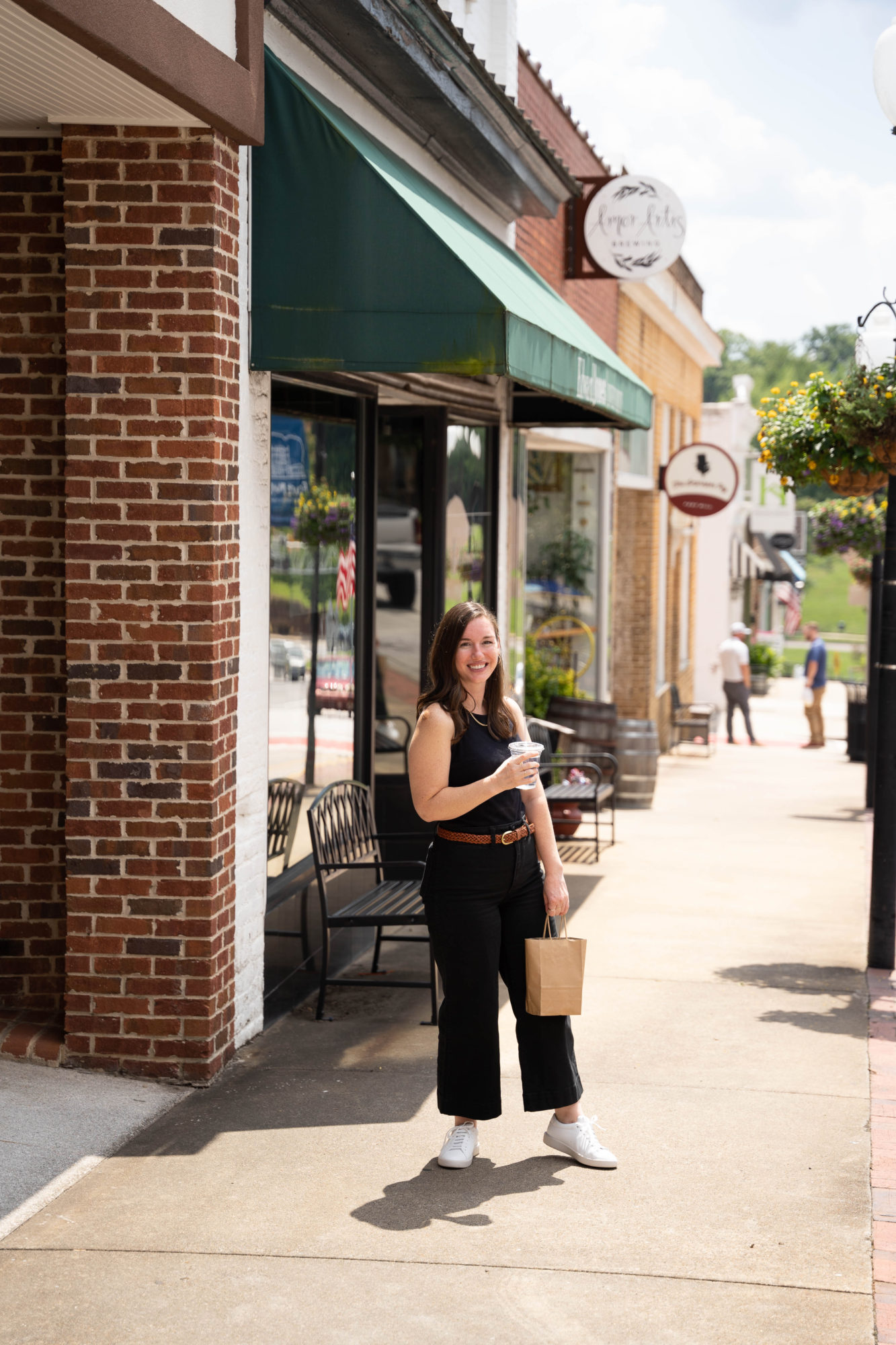 Alyssa stands in downtown Fort Mill with a shopping bag and a cup of water