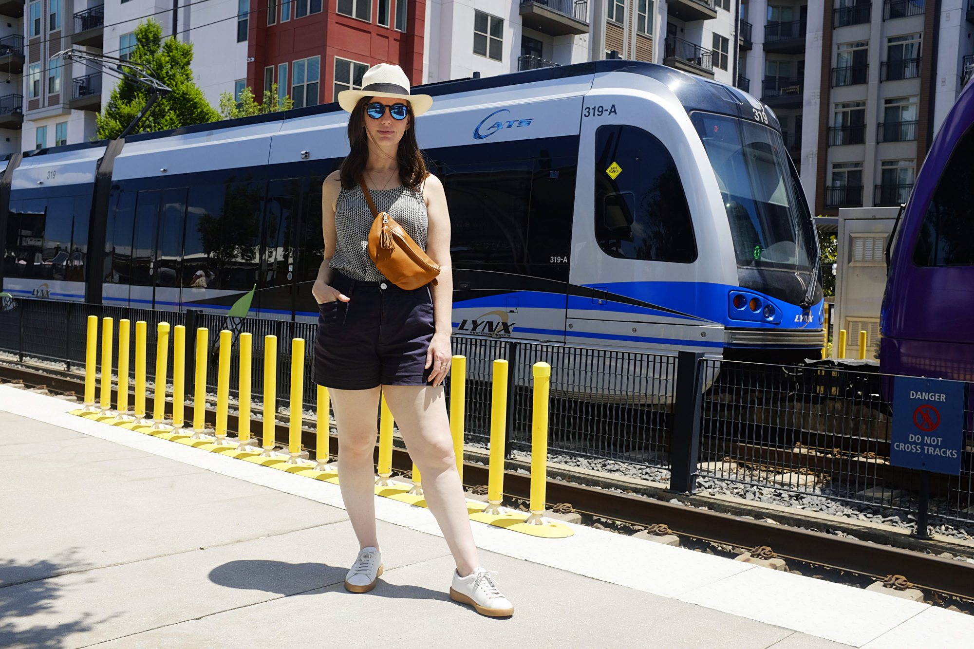 Alyssa wears the Sodo Belt Bag in front of a light rail train