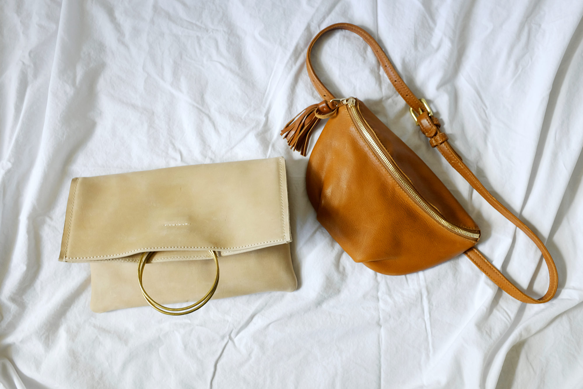 The Nyala Foldover Clutch and Soto Belt Bag on a white textile background