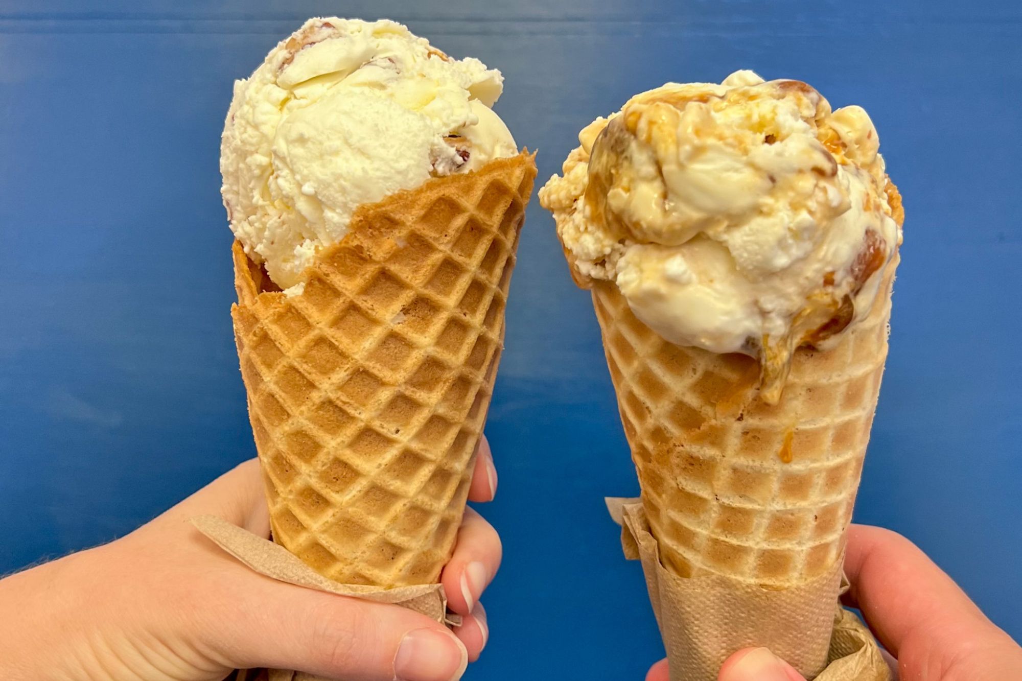 Alyssa and Michael hold ice cream cones on a blue background