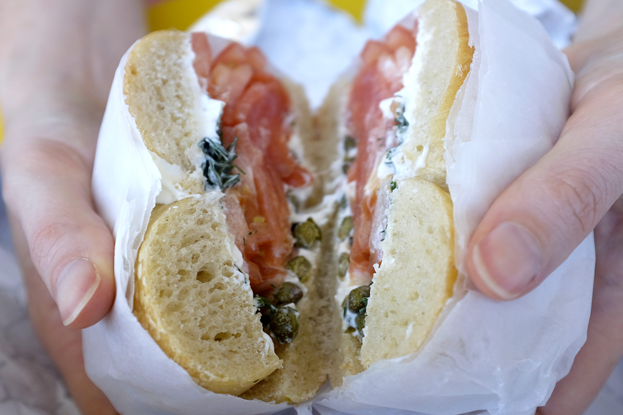 Alyssa holds open a bagel from Brandwein's Bagels