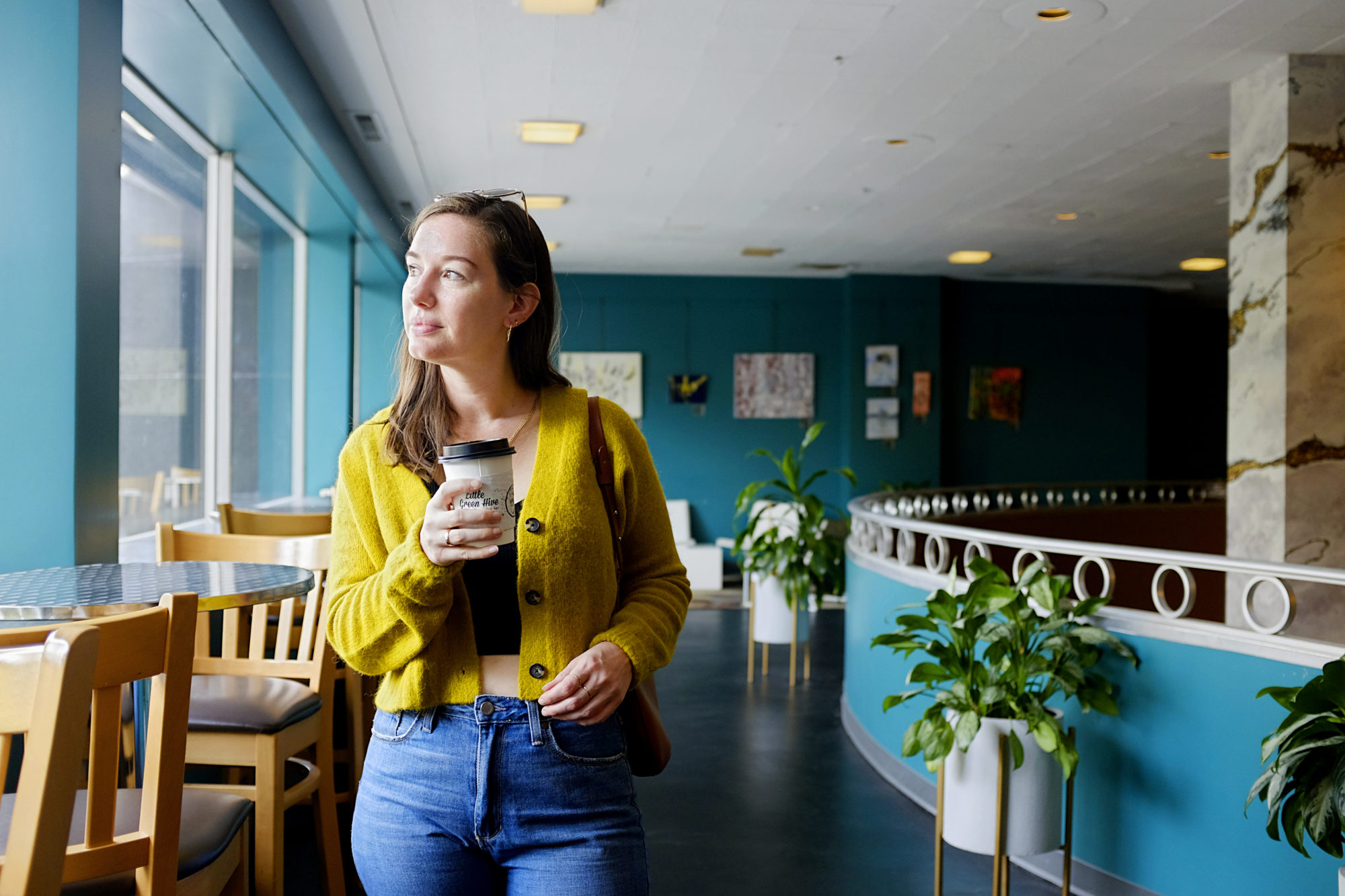 Alyssa holds a cup of coffee from Little Green Hive