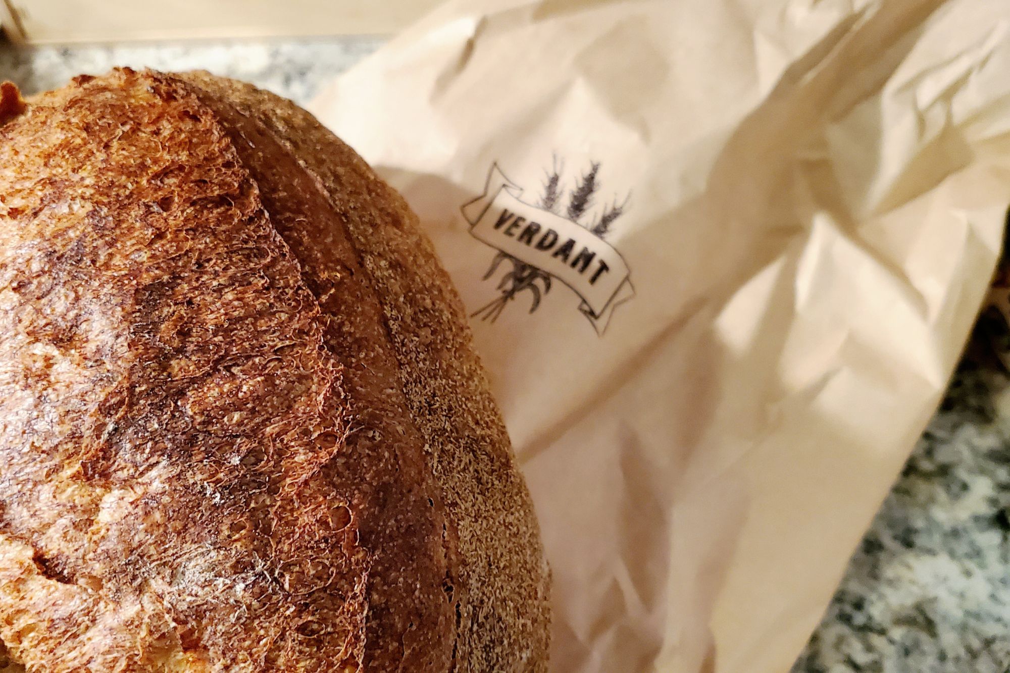 Close up of a loaf of bread and a Verdant paper bag