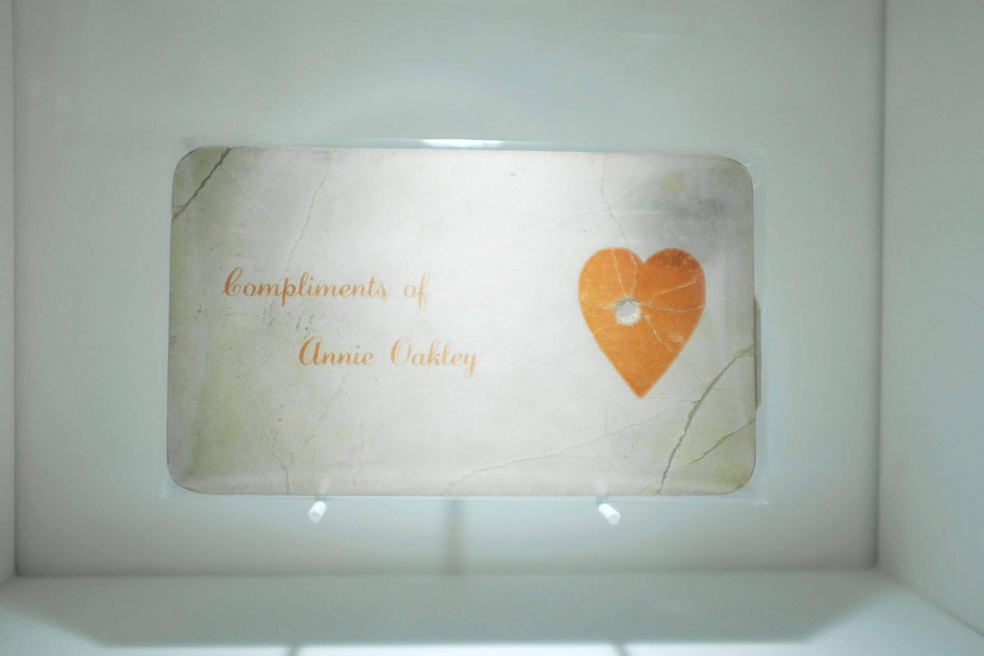 Annie Oakley card with a bullet hole in the heart