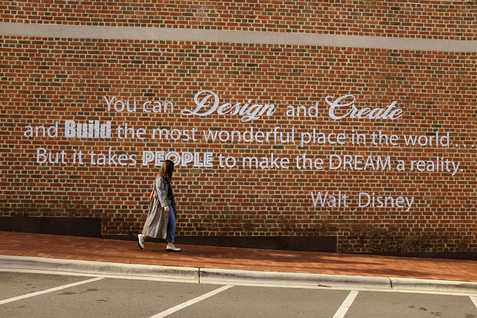 Alyssa walks past a mural with a quote from Walt Disney