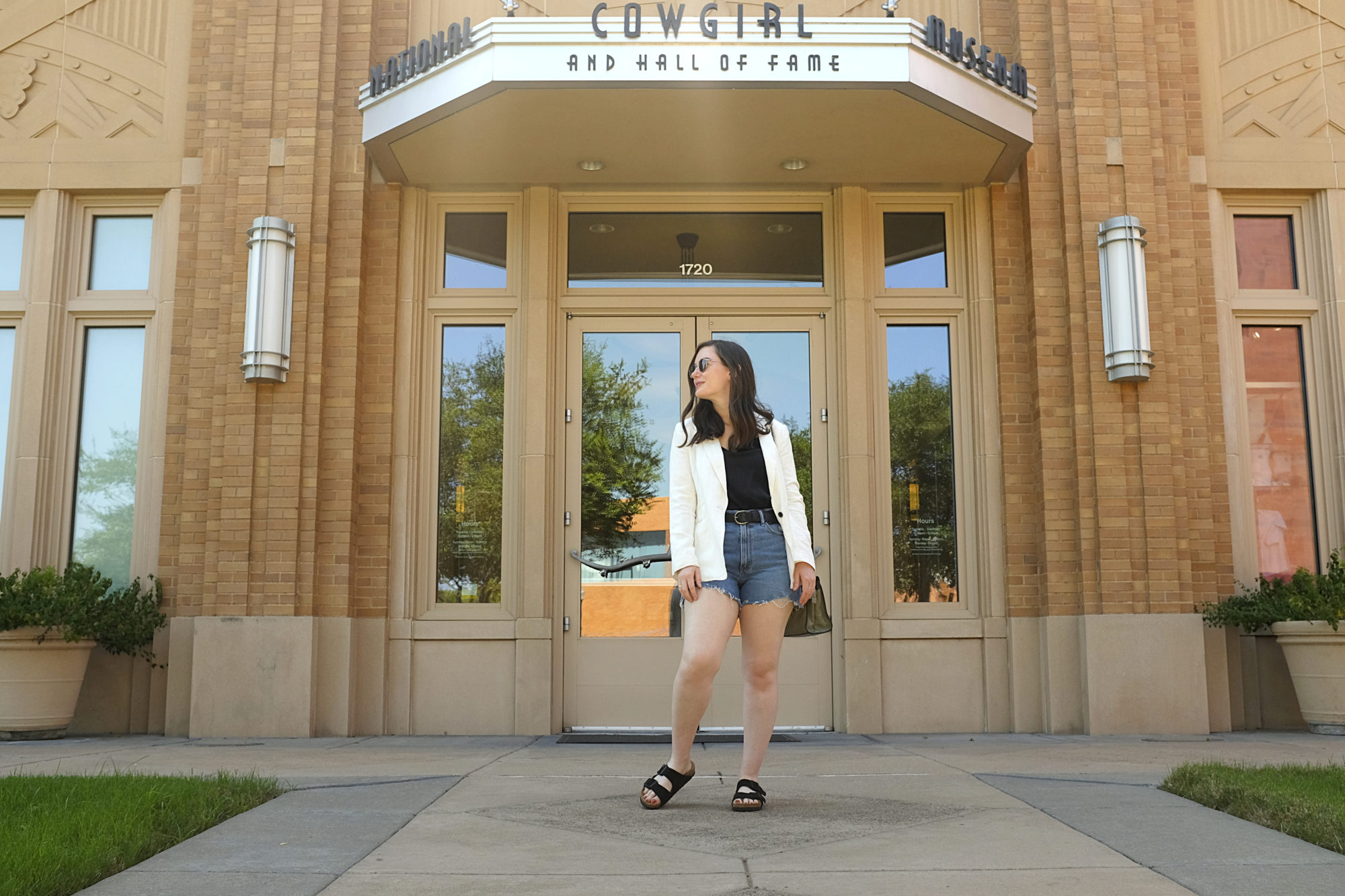 Alyssa wears a black tank, denim shorts, and a white blazer in Fort Worth