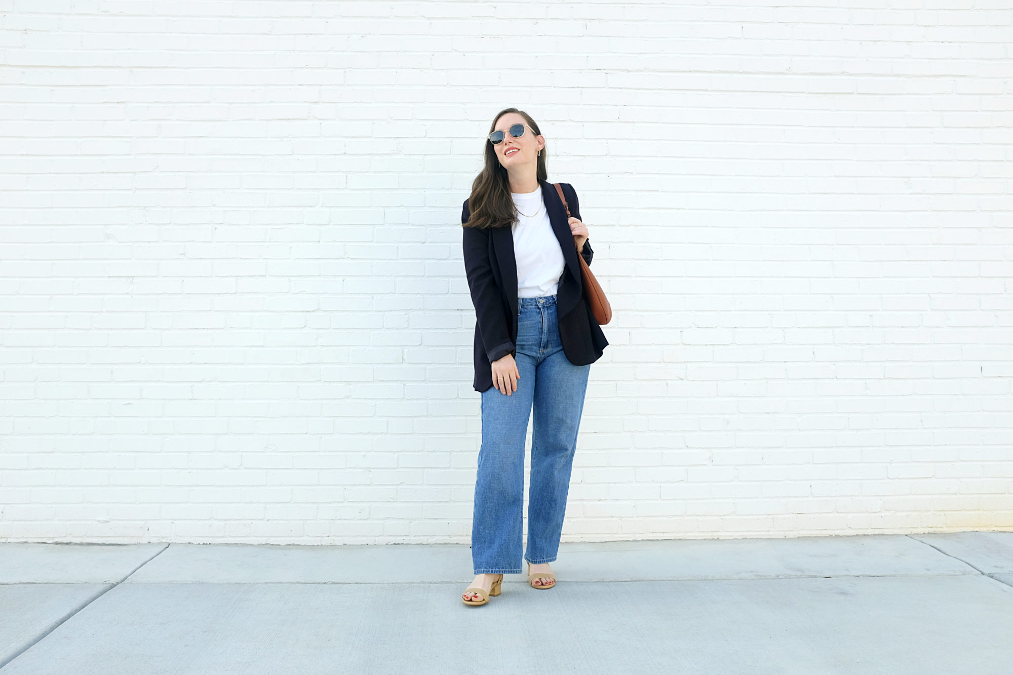 Alyssa wears the Perfect Block Sandal from Sarah Flint in front of a white brick wall