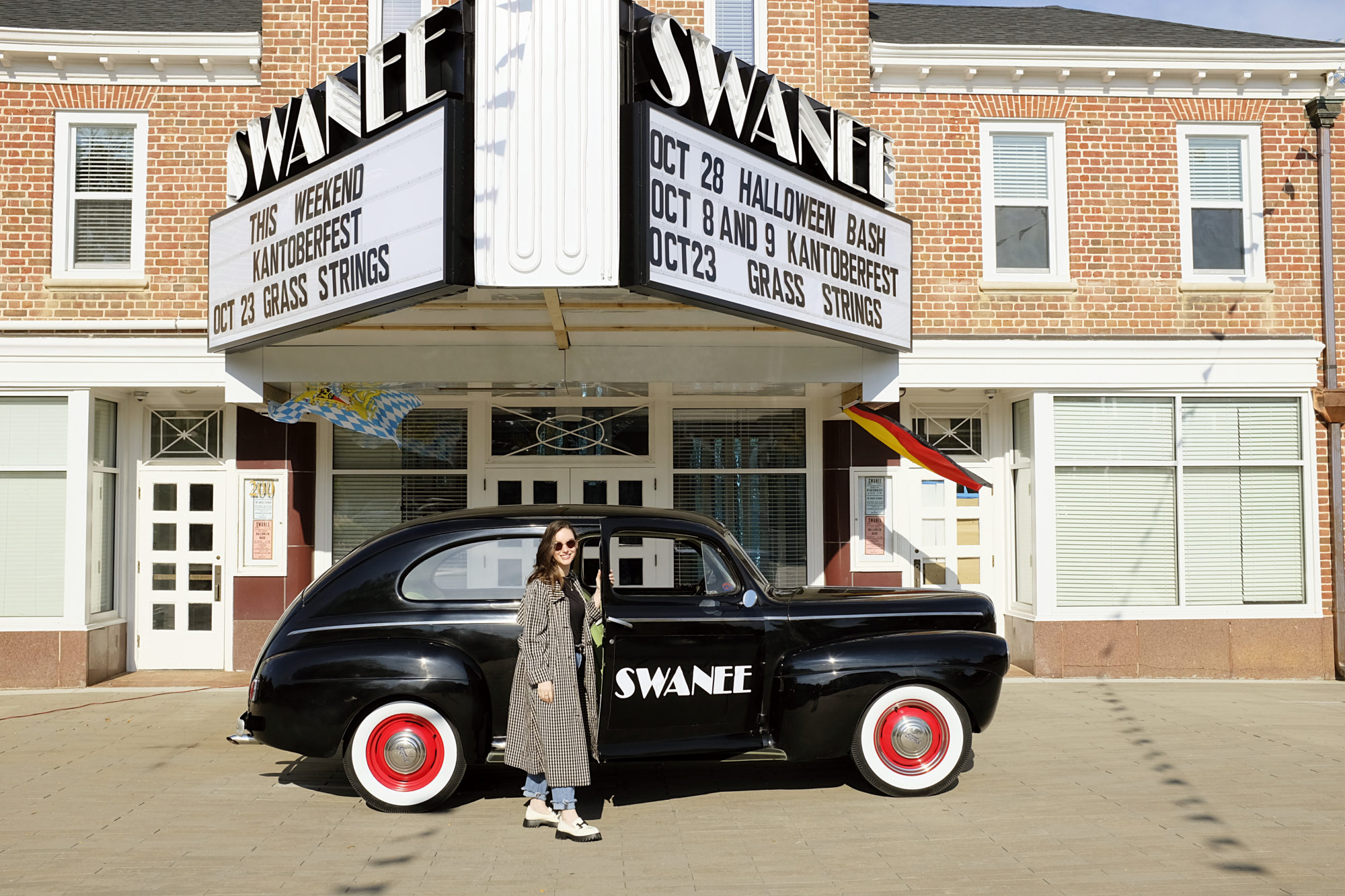Alyssa stands in front of a vintage car below the marquee of Swanee Theatre