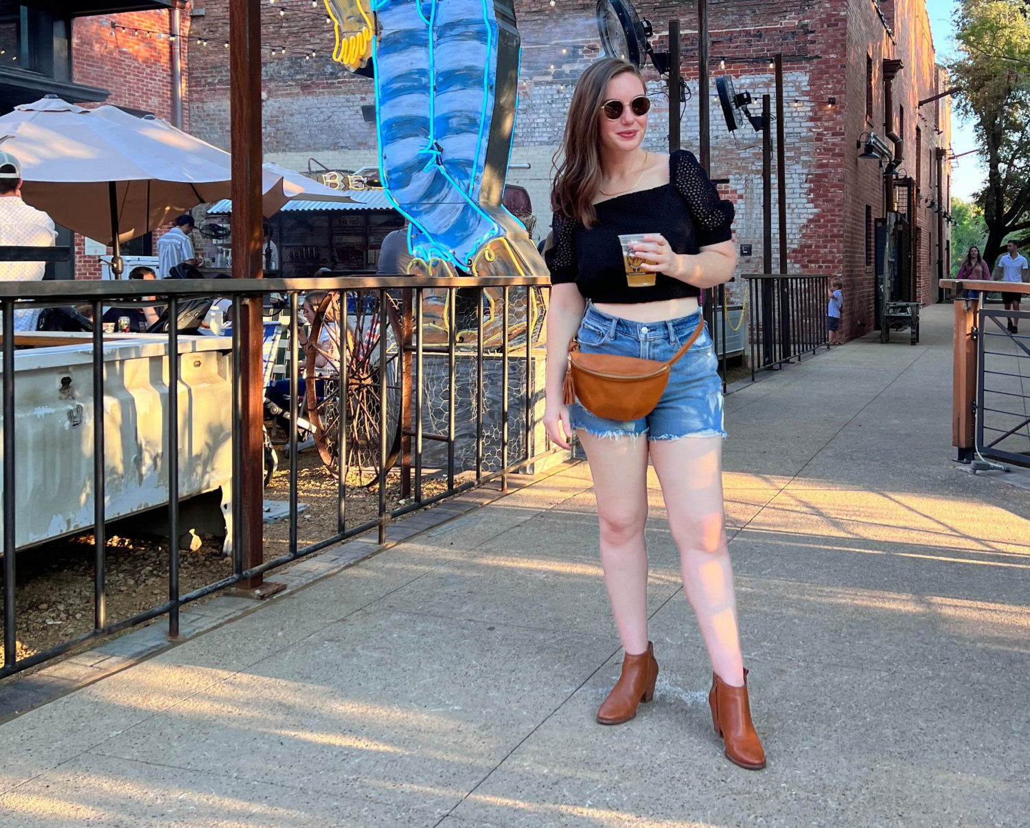 Alyssa wears a black eyelet top, denim shorts, and brown boots