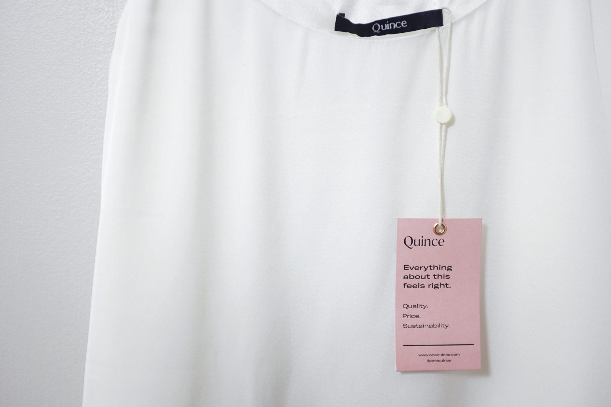 Closeup of a white silk cami with a Quince tag