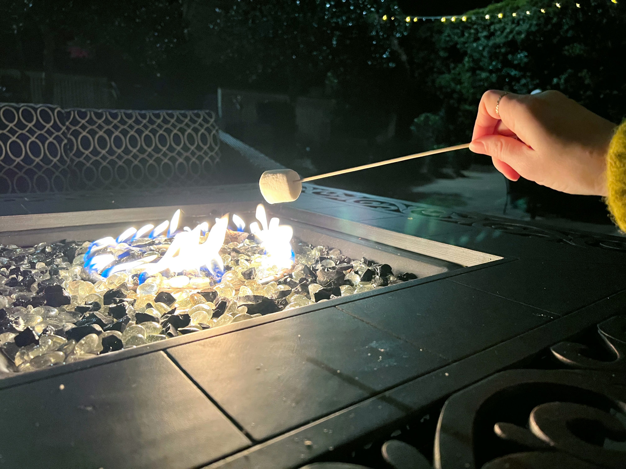 A hand makes smores over a fire pit