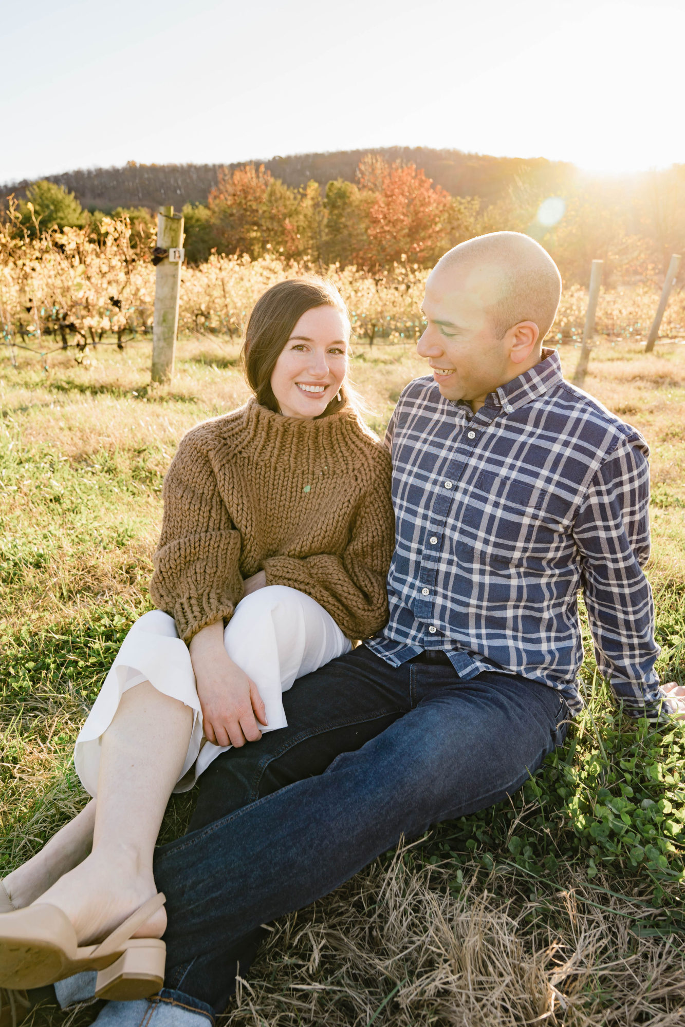 Alyssa and Michael sit on the ground in a vineyard together