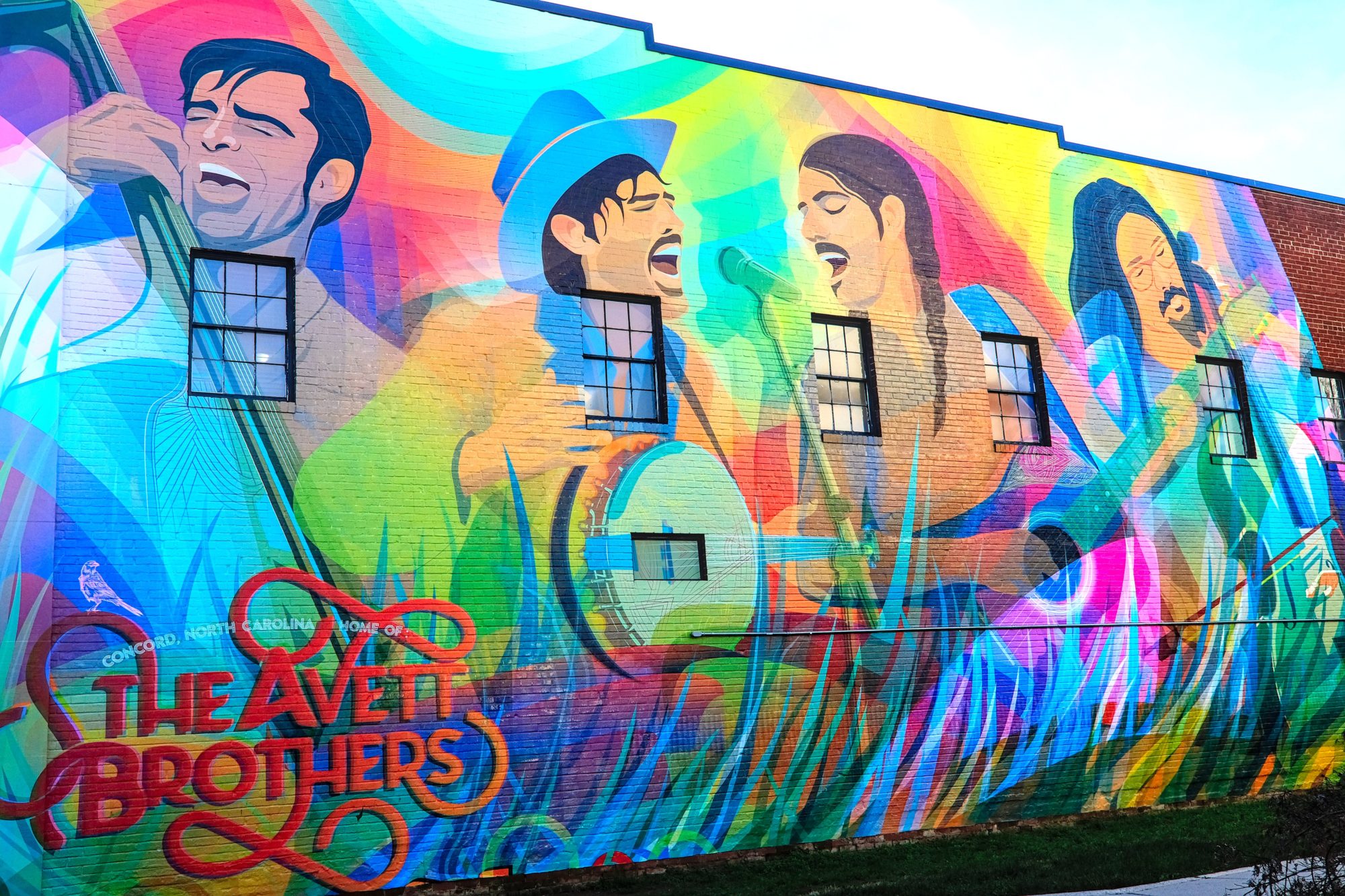 A large, colorful mural of The Avett Brothers in Concord