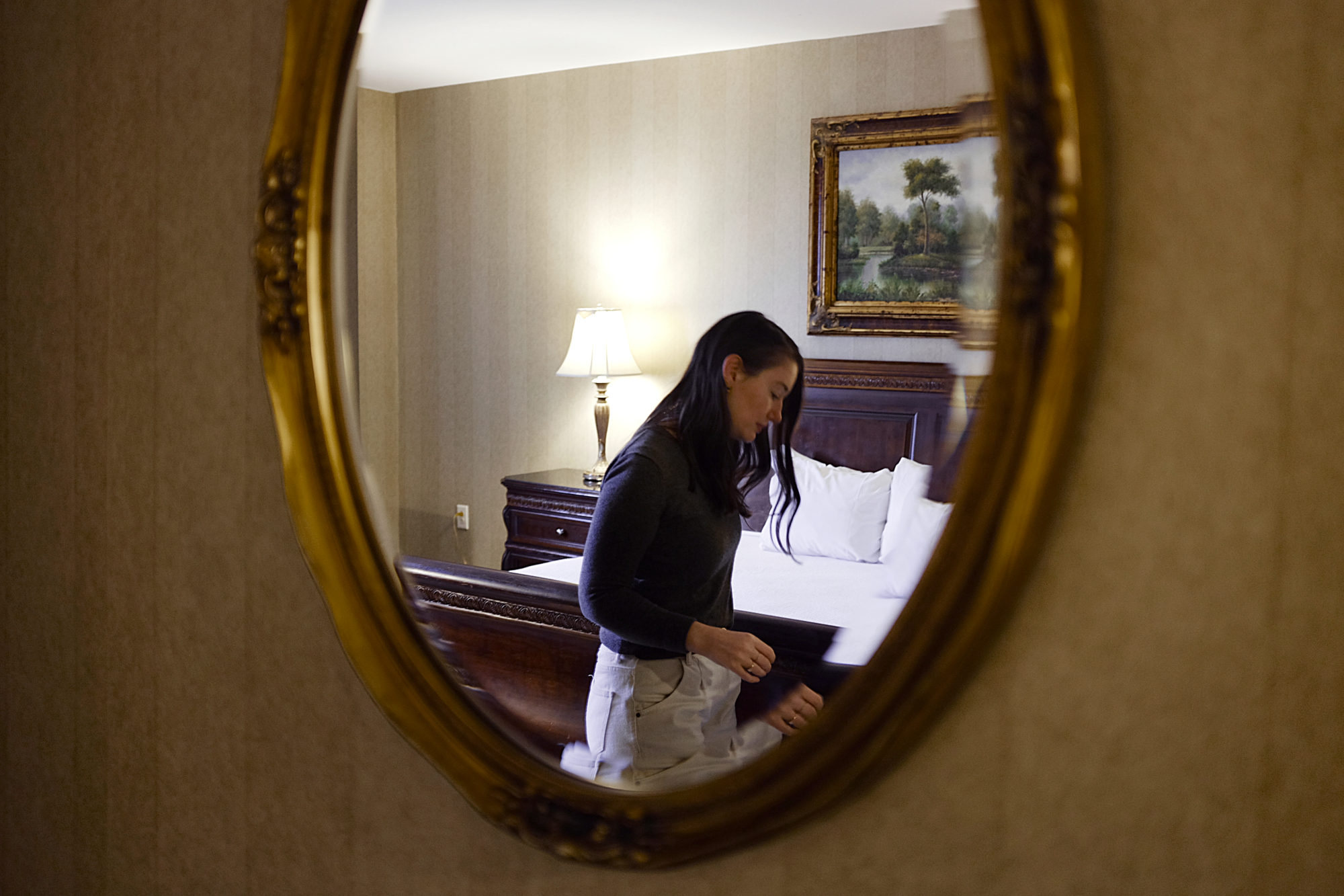 Alyssa is seen through a mirror in a hotel room