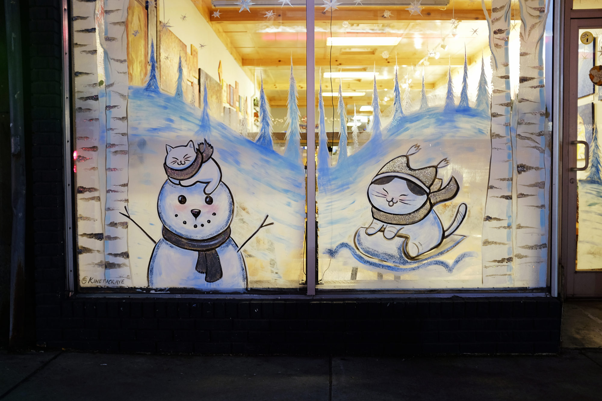 Window of Dos Gatos coffeeshop with a winter snowman scene