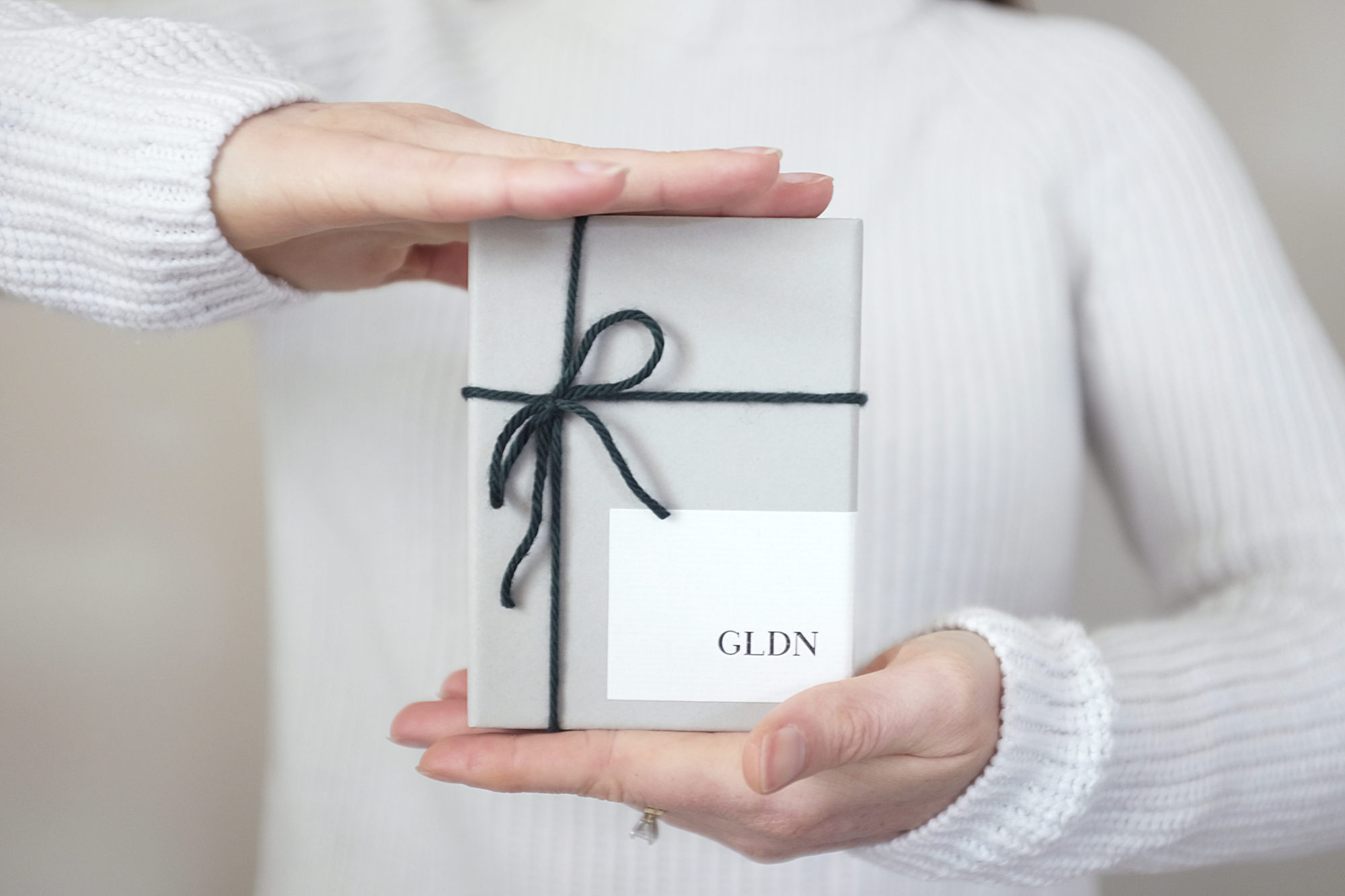 A close up of Alyssa holding a GLDN box in her hands; it is tied with a yarn bow