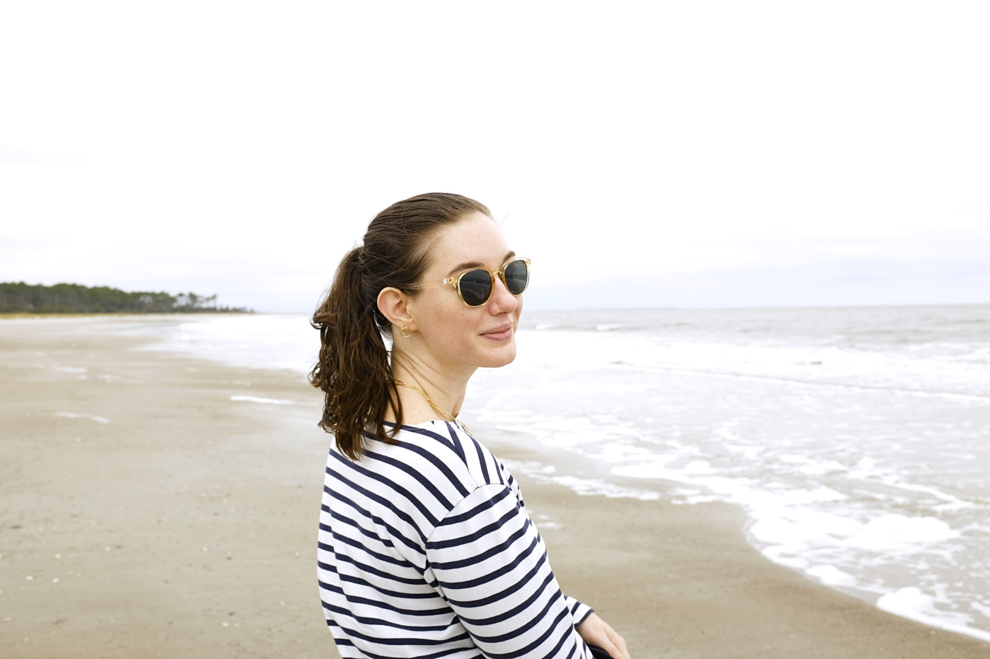 Alyssa wears a striped shirt on the beach