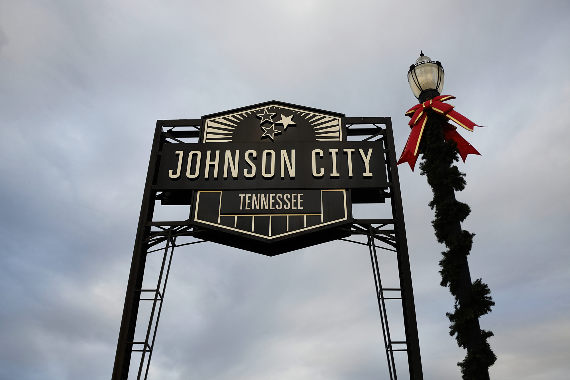 View of the Johnson City sign with a garland-wrapped light pole next to it