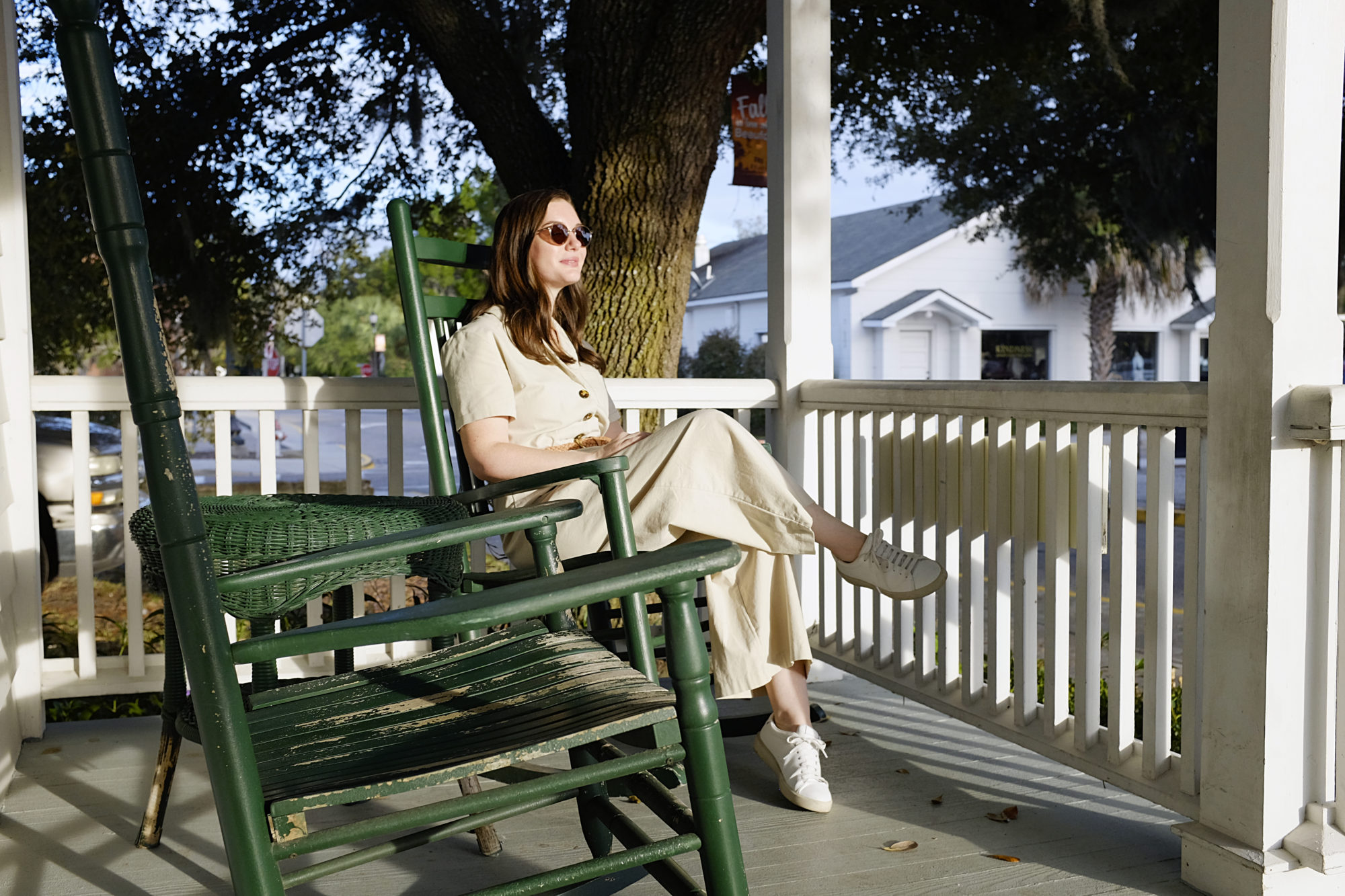 Alyssa wears a tan jumpsuit and sits in a rocking chair