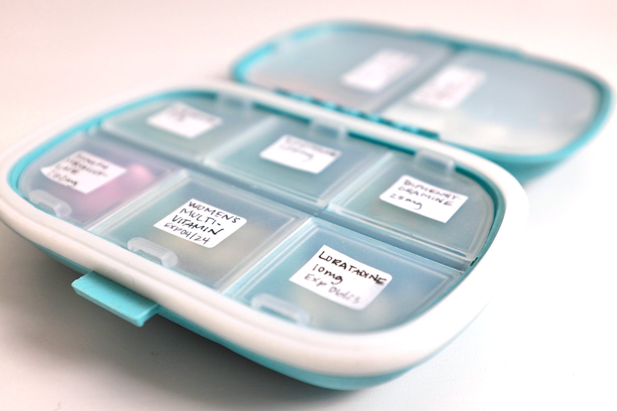 An open pillbox containing pills and a label for each one