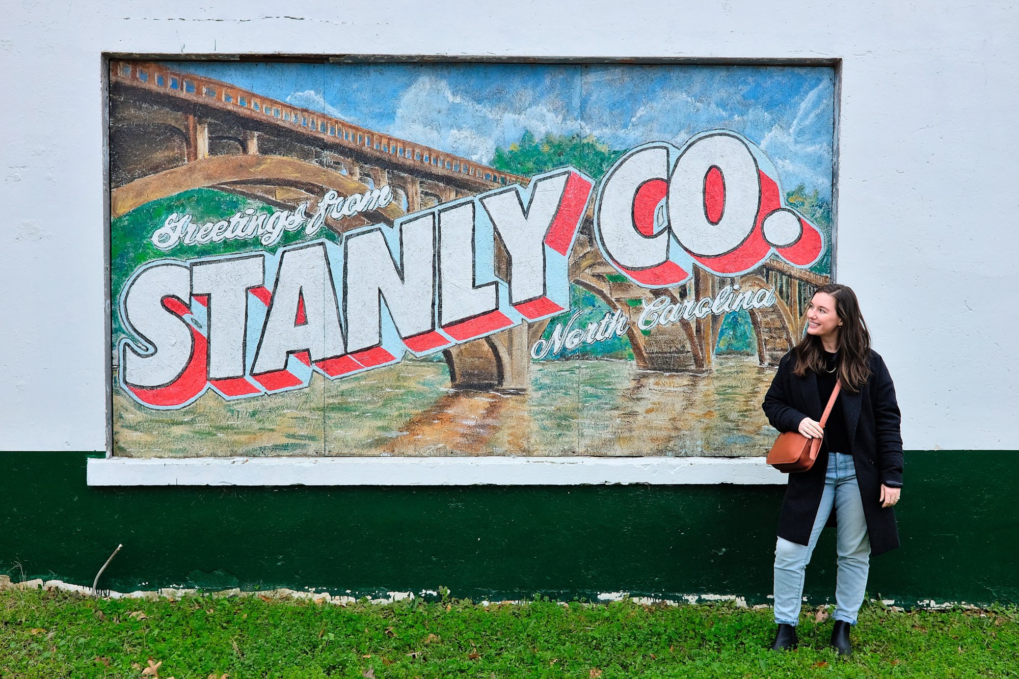 Alyssa stands in front of a mural that reads "Greetings from Stanly County"
