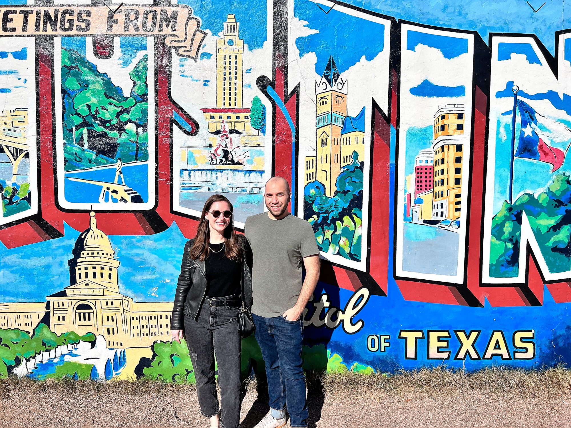 Alyssa and Michael stand in front of the Greetings from Austin Mural