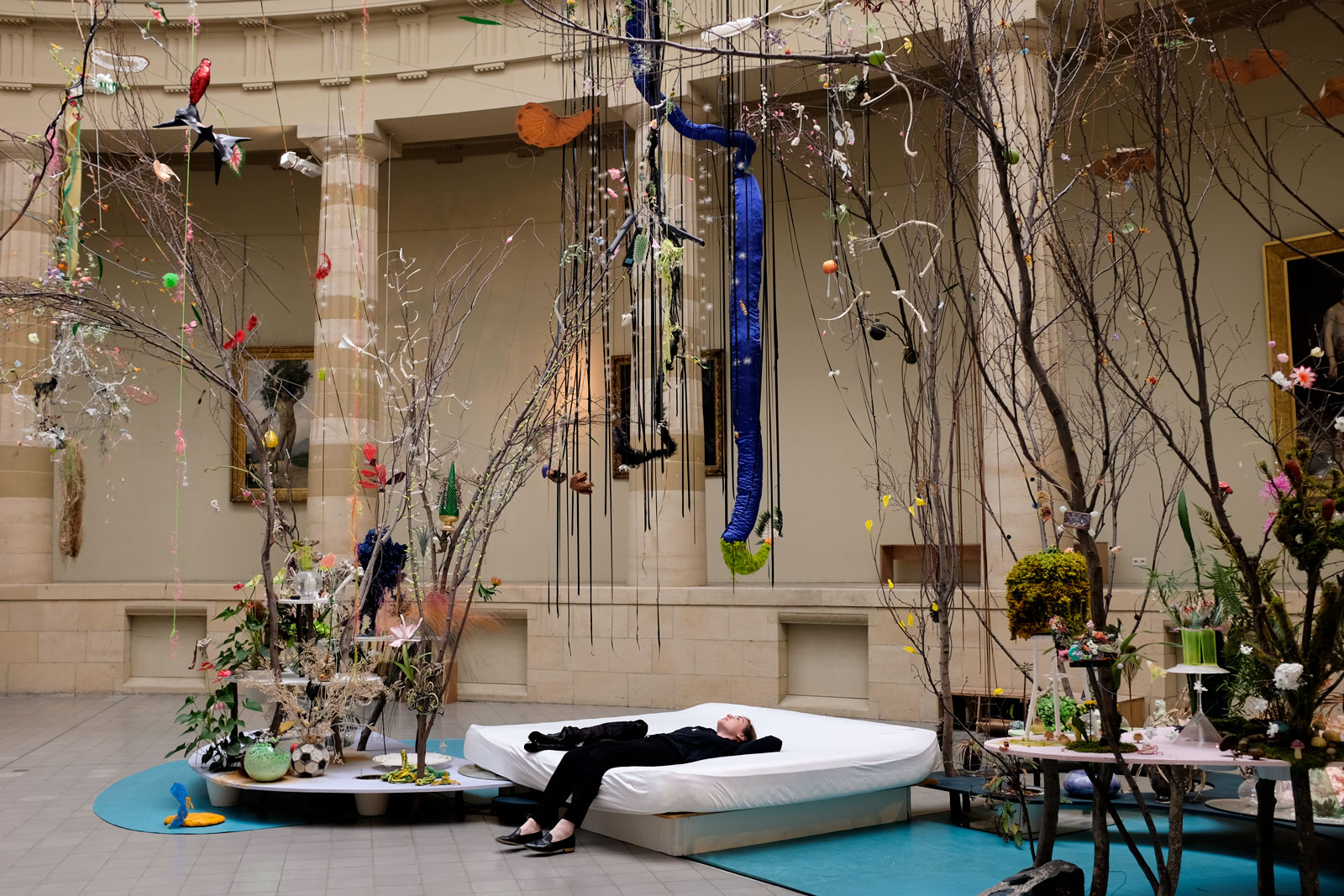 Alyssa lies down on a mattress and peers up at art in a Ghent museum