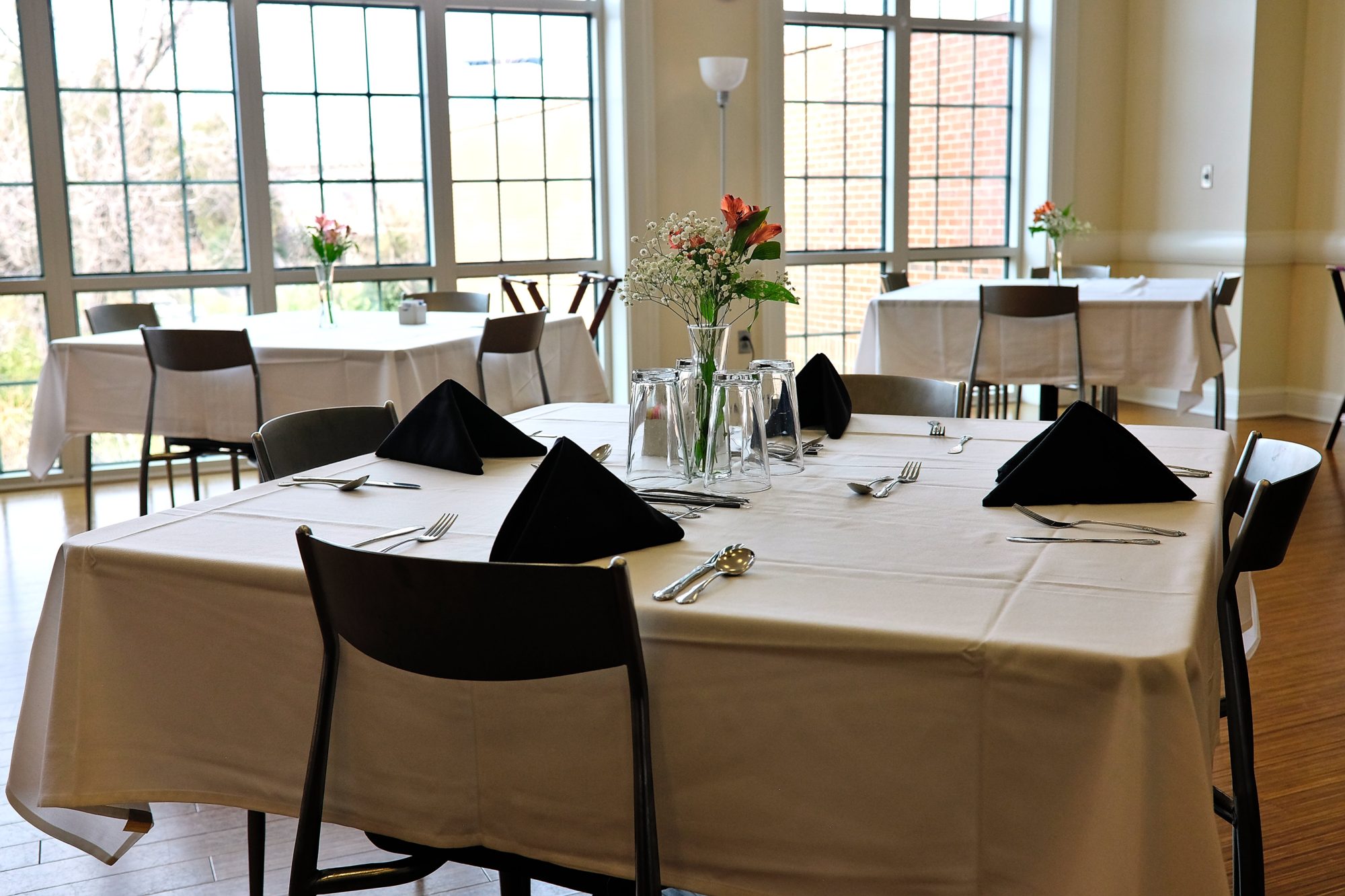 A well-lit dining room with tables set for fine dining service