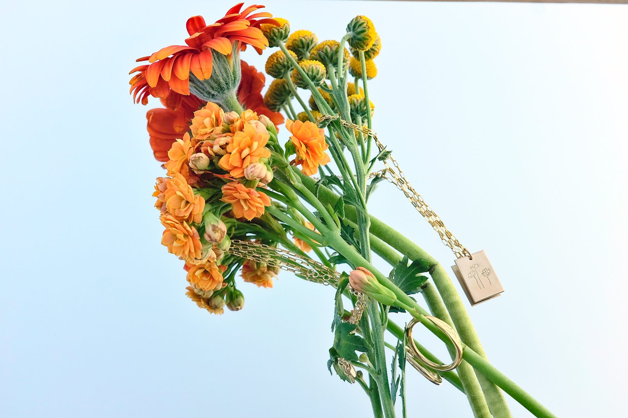 GLDN's Marseille necklace and olive signet ring are mixed in with a bouquet of flowers