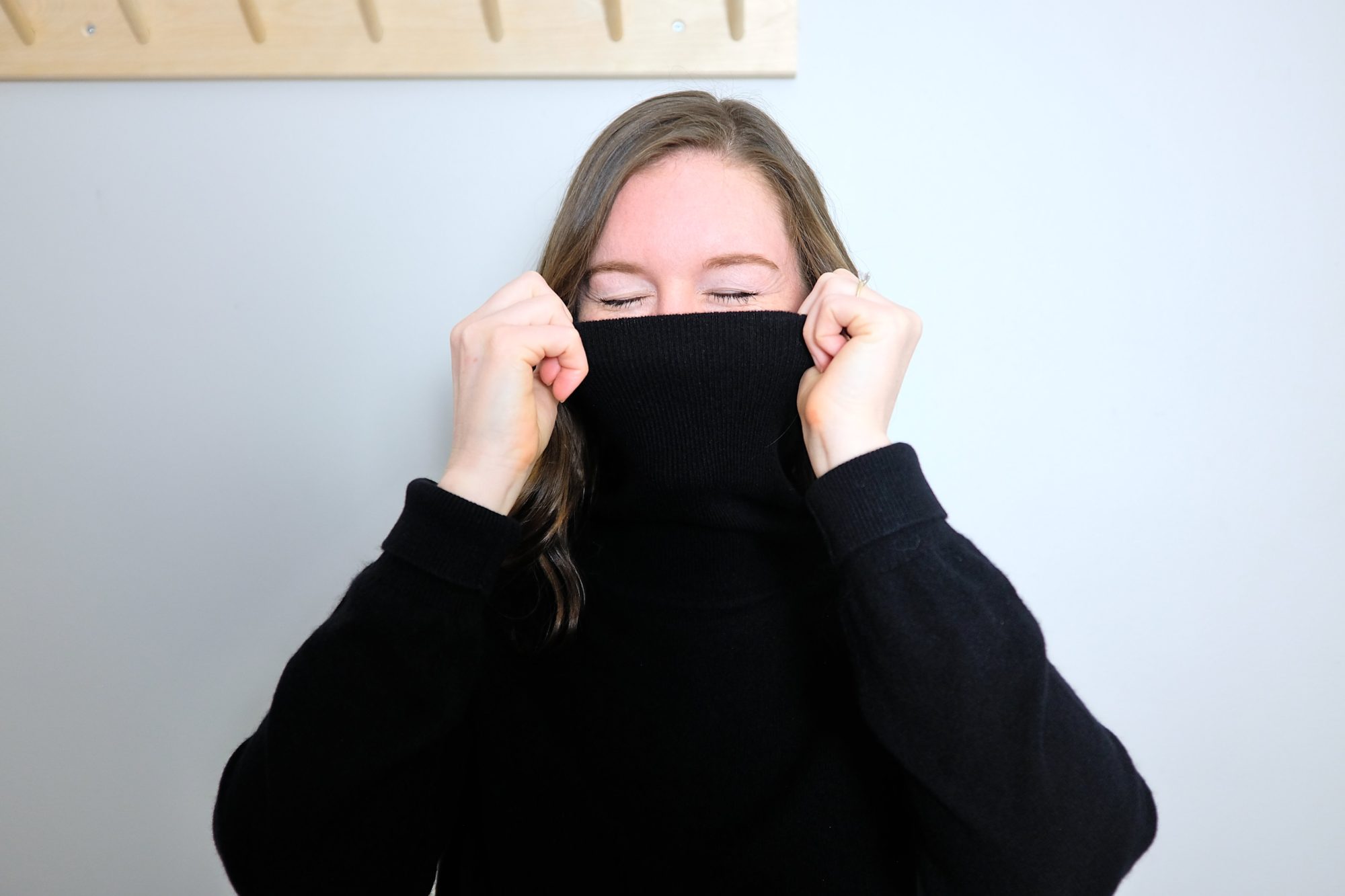 Alyssa folds a black turtleneck over her face