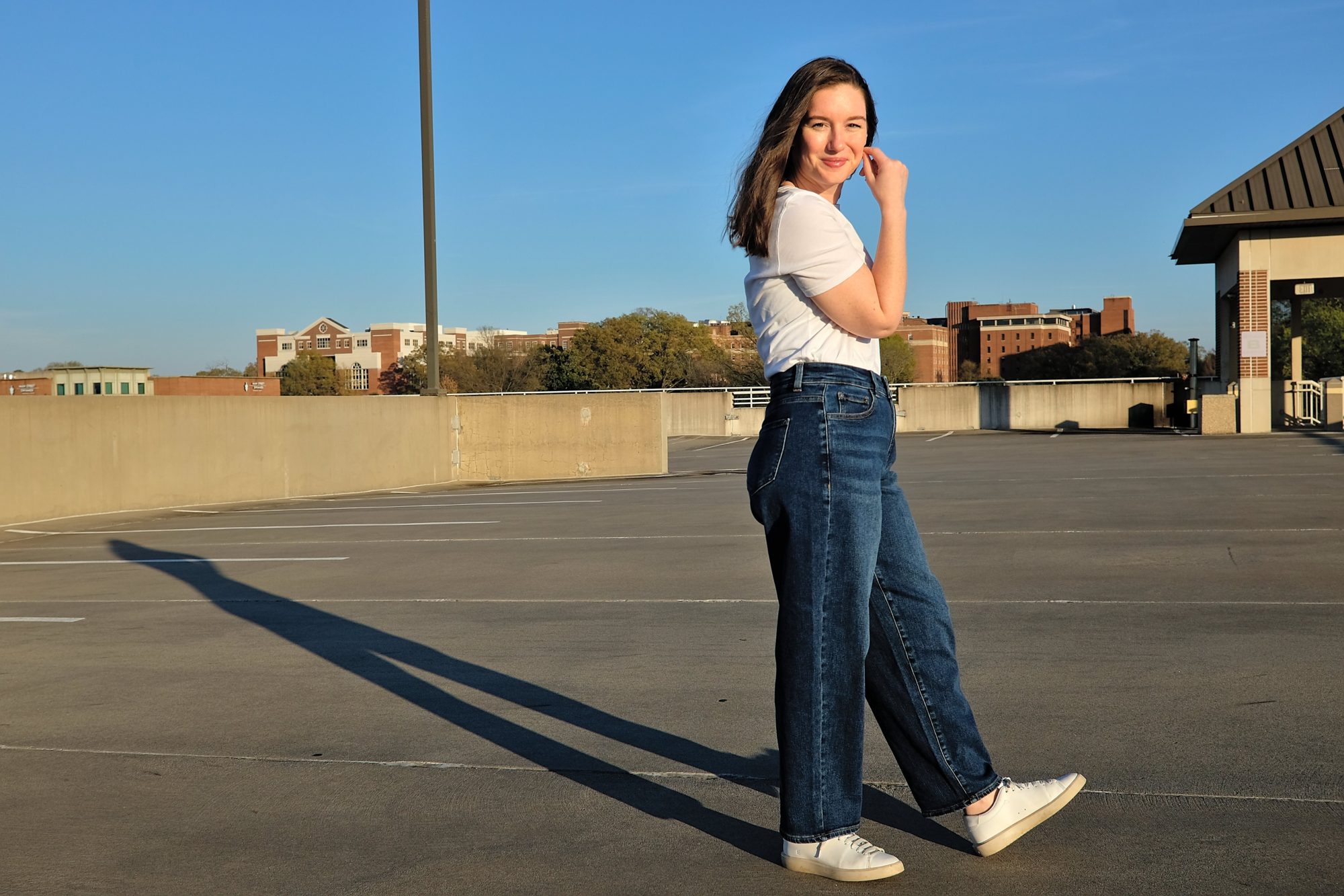 Alyssa wears the Lou High Rise Barrel Leg jean with a white tee and sneakers and faces to one side