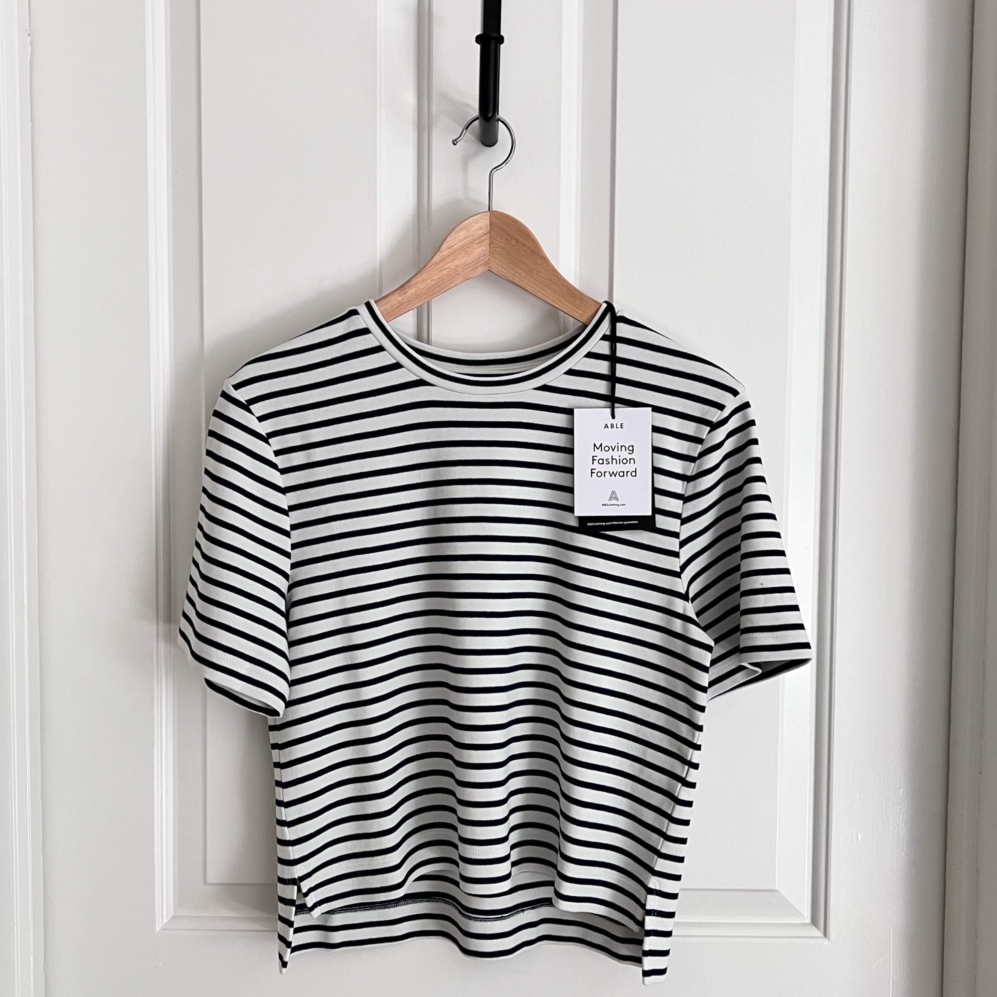 A striped tee hangs from a wooden hanger