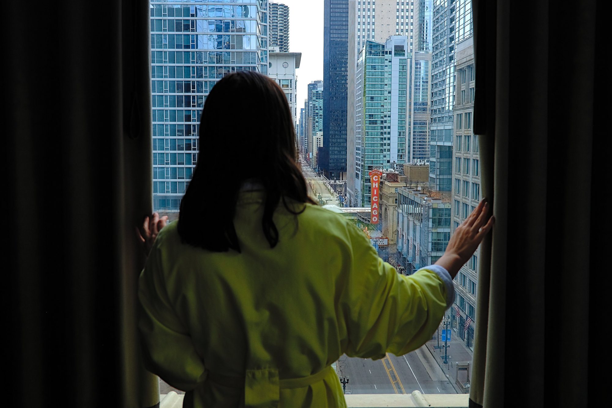 Alyssa looks out the window in a yellow bathrobe