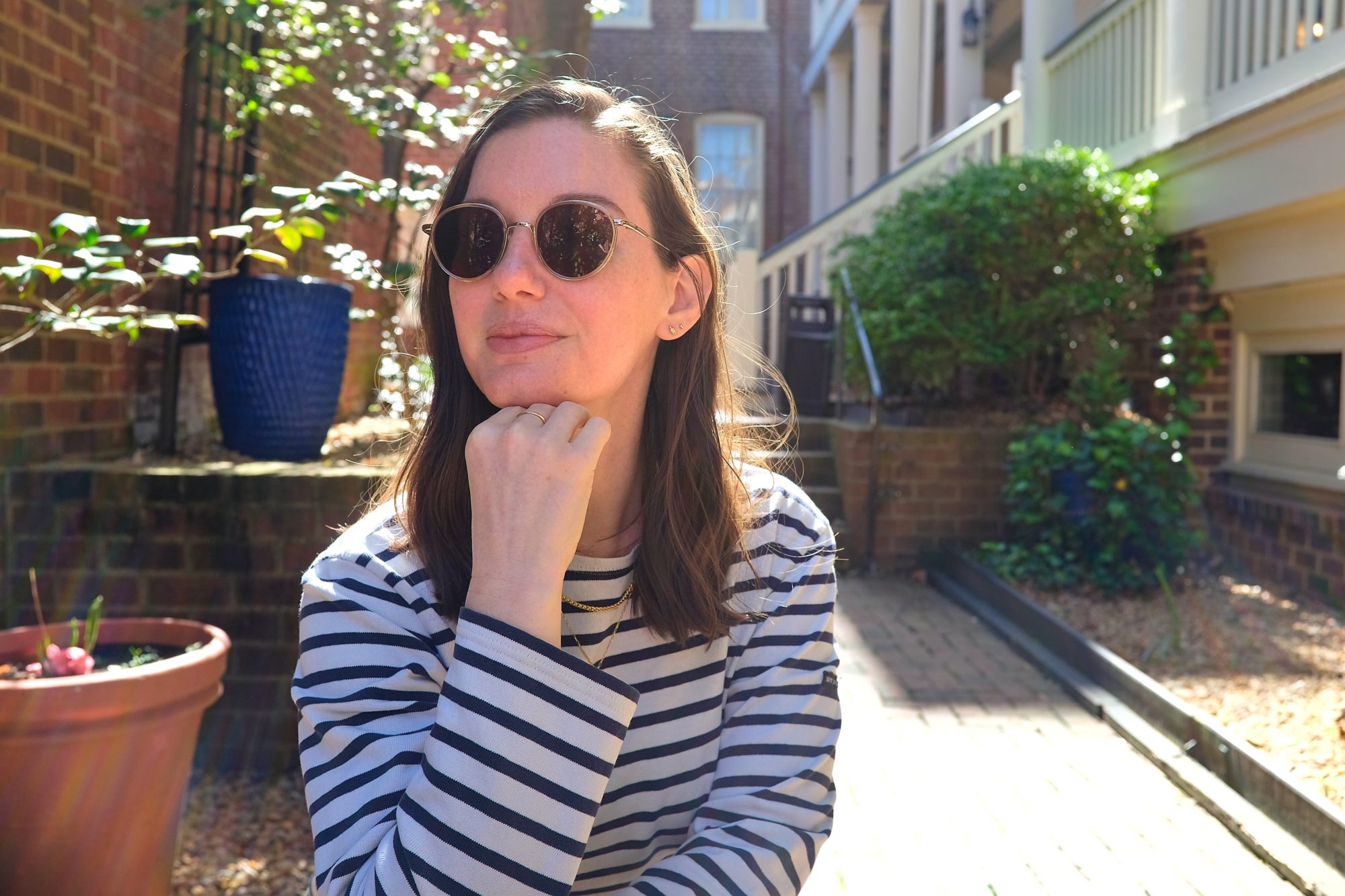 Alyssa rests her head on her chin at a table in a courtyard