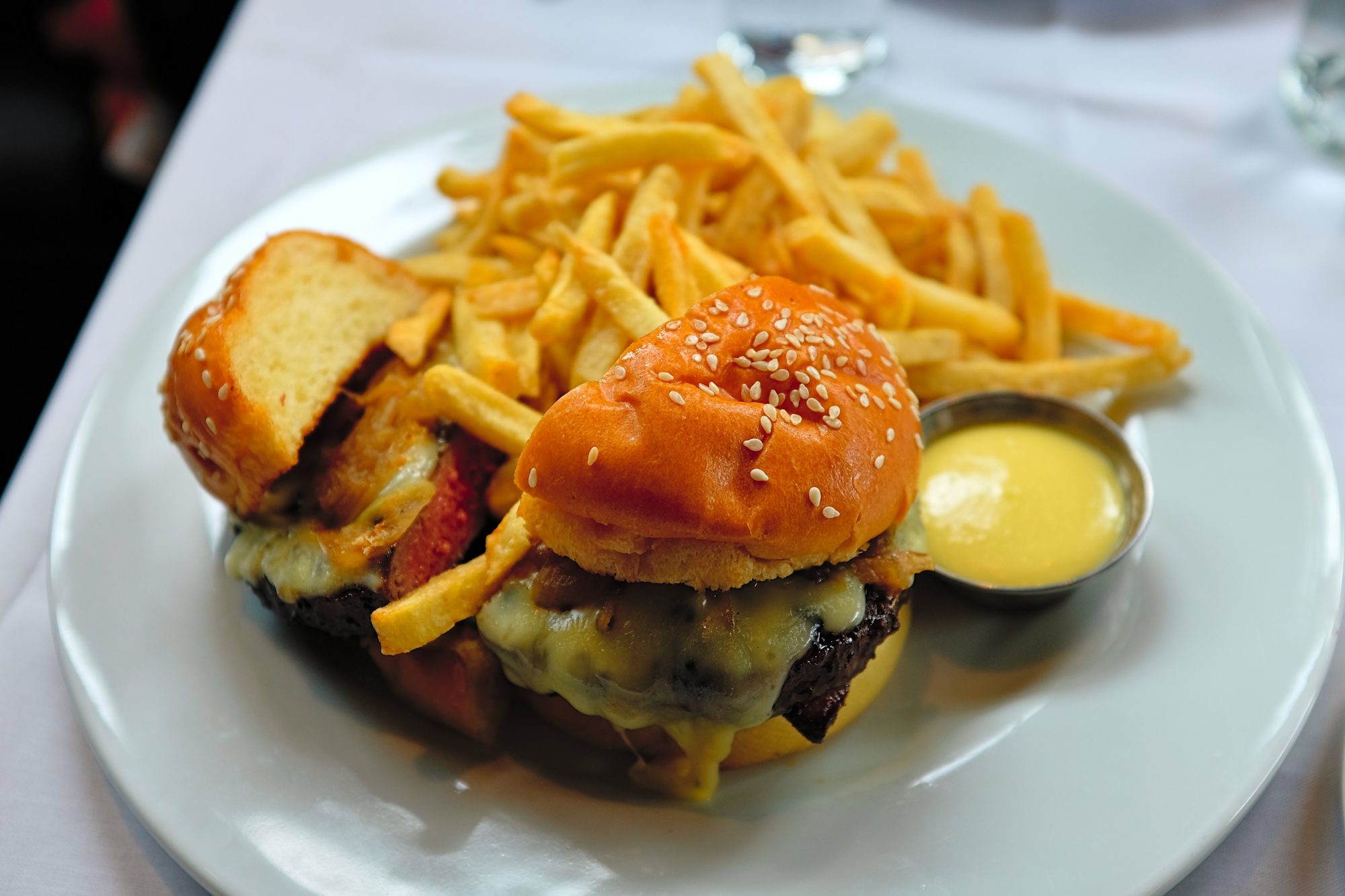 A burger is sliced in two and served with an abundance of fries